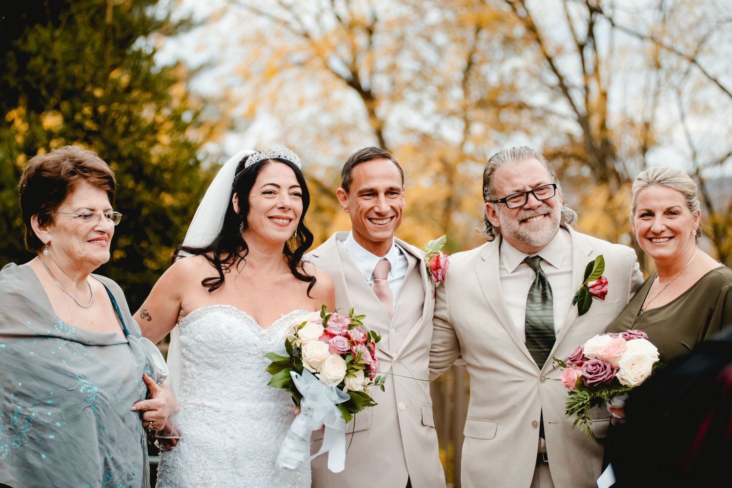The bride, the groom, the best man, the maid of honor, and the mother of the bride pose together smiling on a beautiful fall day in New York