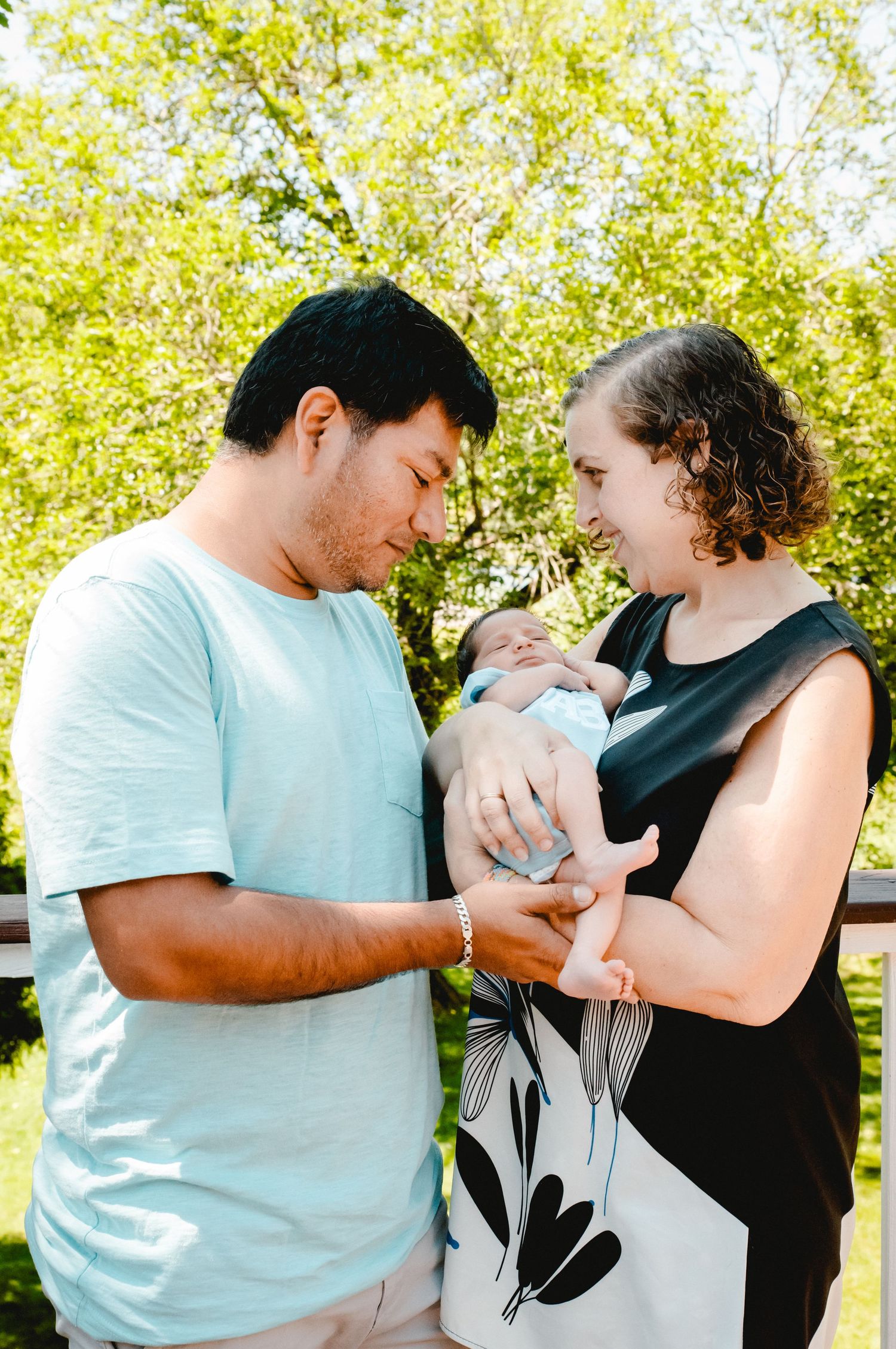 New parents hold their son in their backyard on a sunny day in Ardsley, NY.
