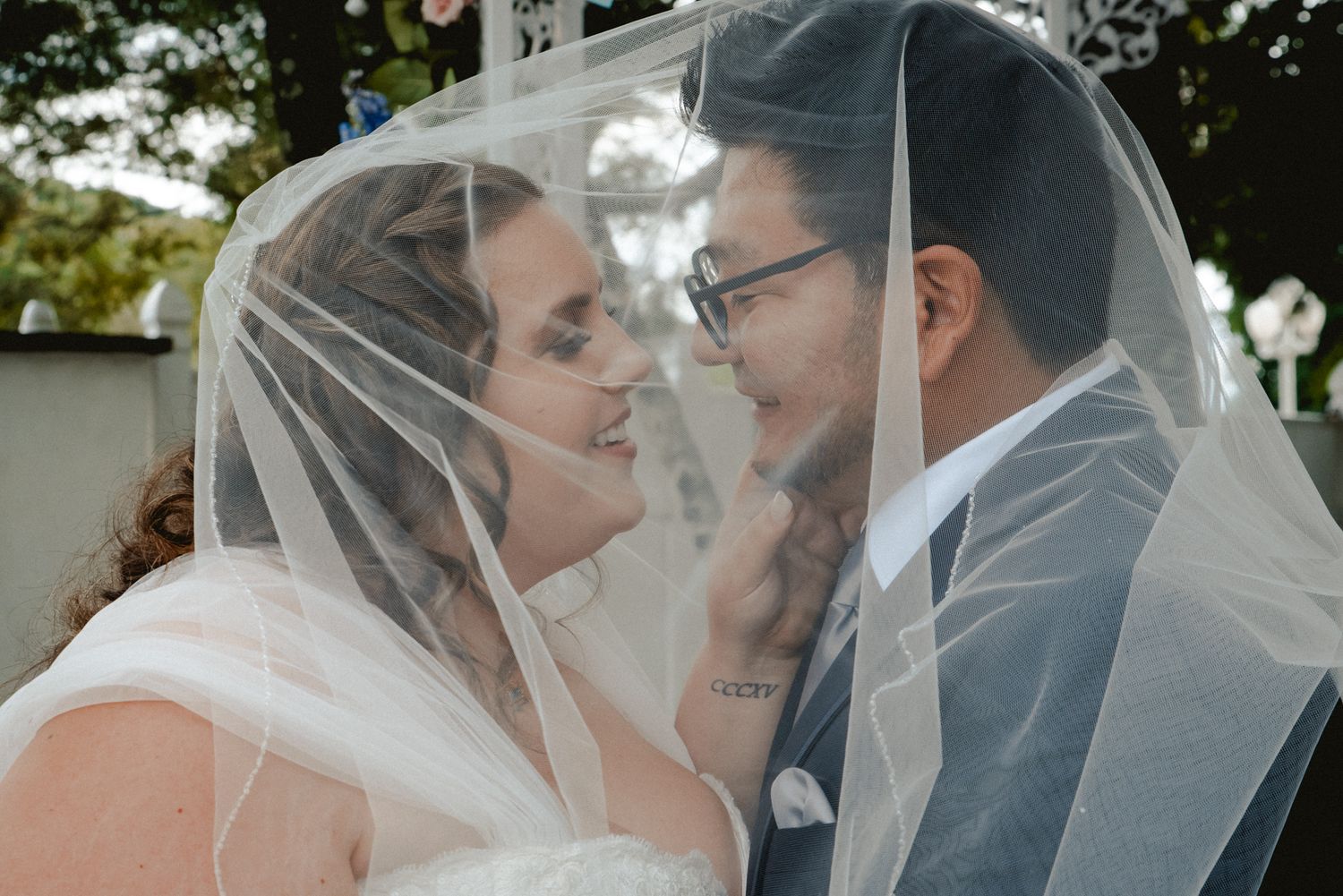 A bride and groom lean in for a tender kiss under the bride's veil just before the ceremony begins in Westchester, NY.