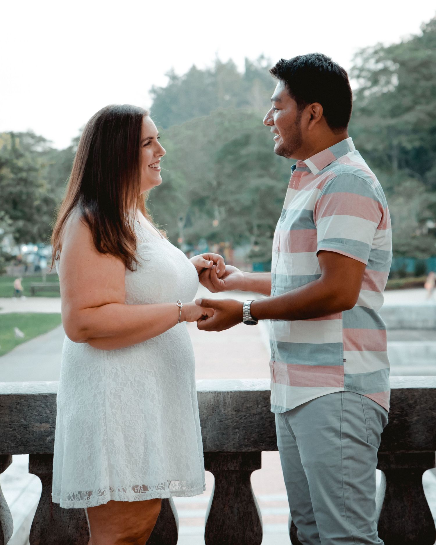 In Westchester, NY at the Kensico Dam Plaza a newly engaged couple hold hands and lock eyes during their engagement photoshoot.