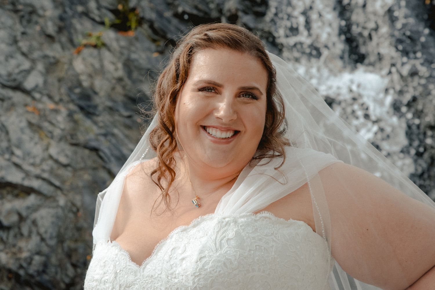 A stunning bride poses for a close up in front of a waterfall in Westchester, NY.