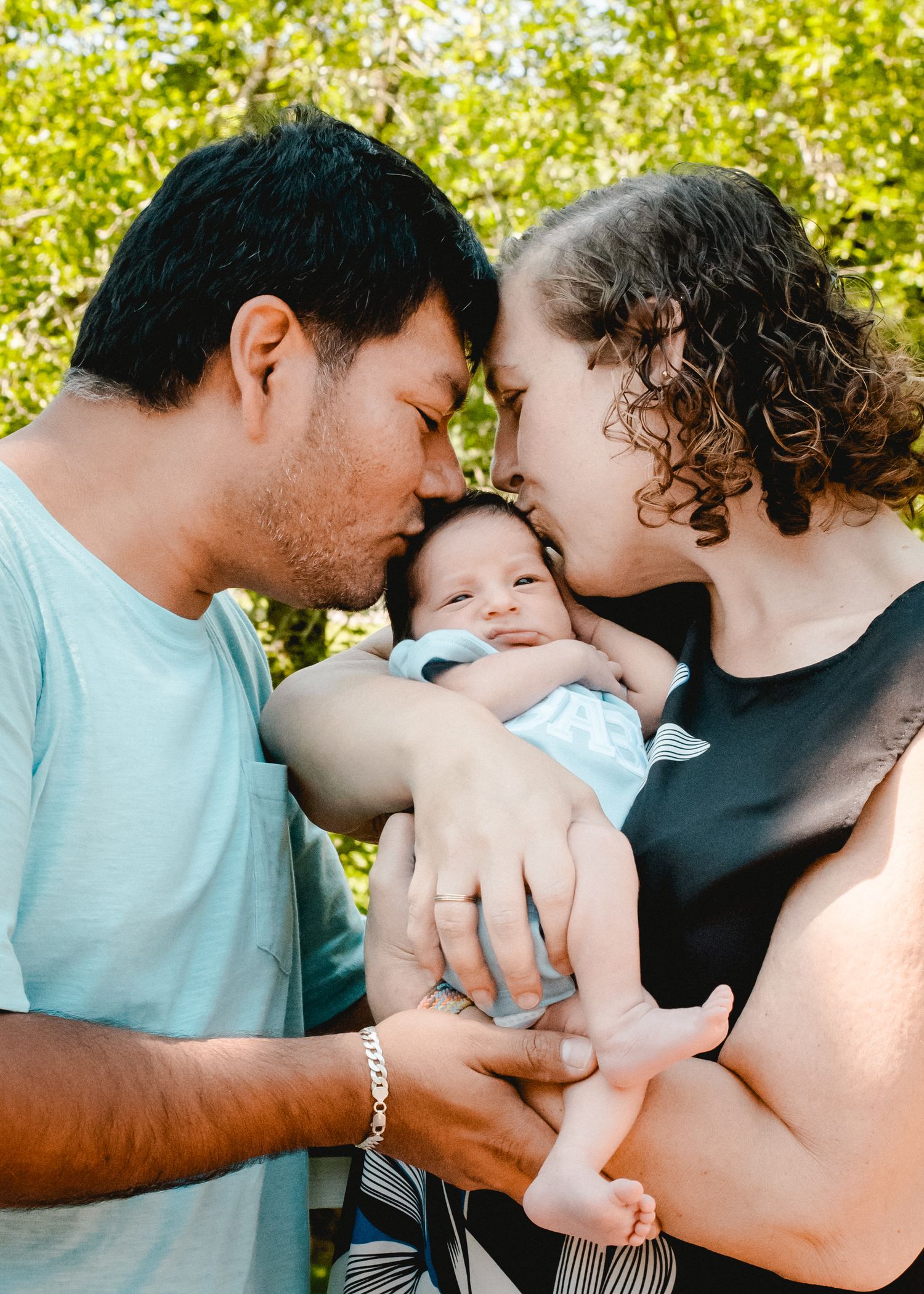 New parents kiss their baby boy on the forehead during a family photo session in Ardsley, NY.