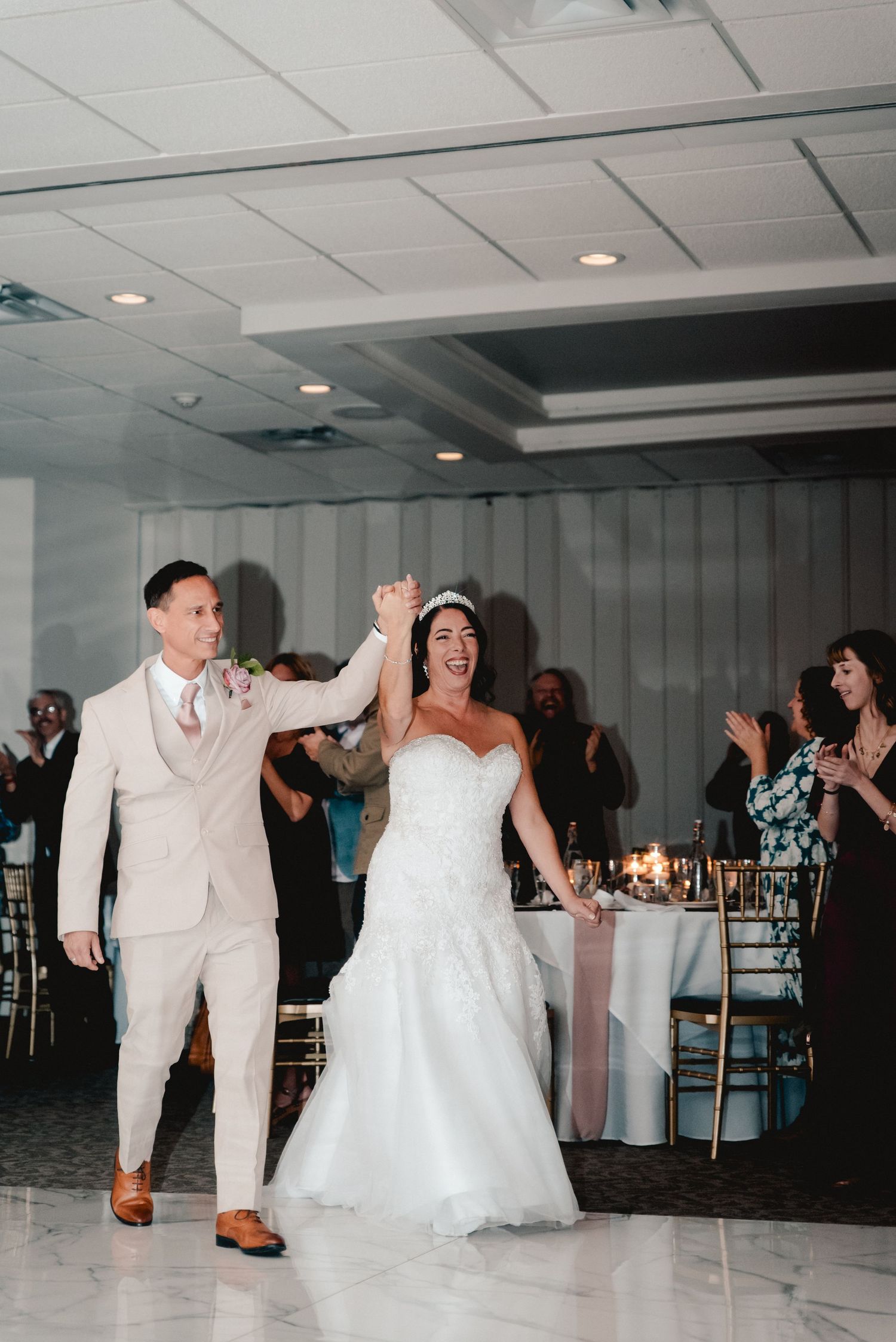 The bride and groom make their grand entrance to the reception as their friends and family cheer. The reception was held in Upstate NY.
