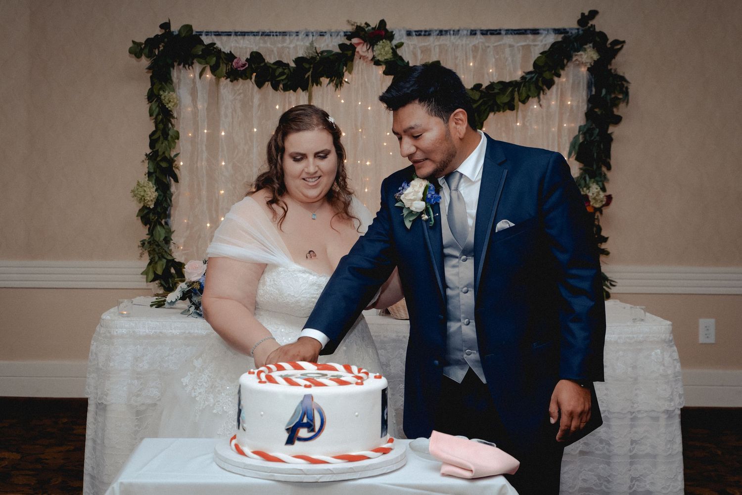 The bride and groom hold hands while cutting their custom wedding cake in Westchester, NY.