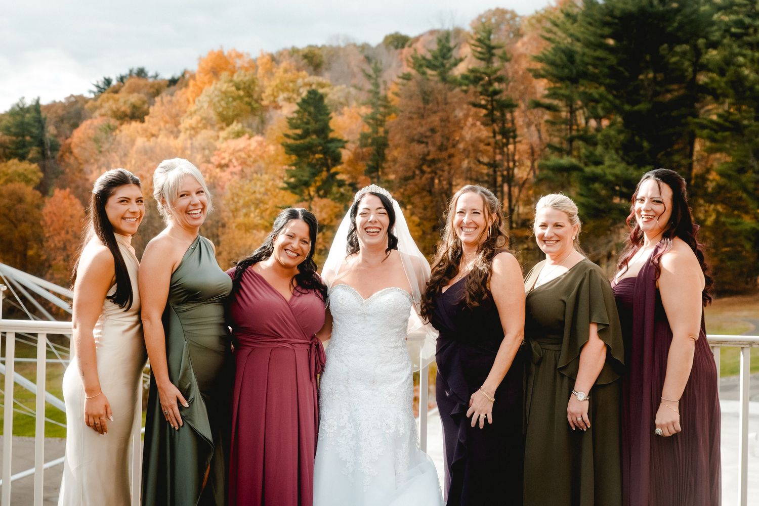 The bride and her bridesmaids in a stunning group photo on a sunny, warm October day surrounded by fall foliage in Johnson City, Upstate NY.