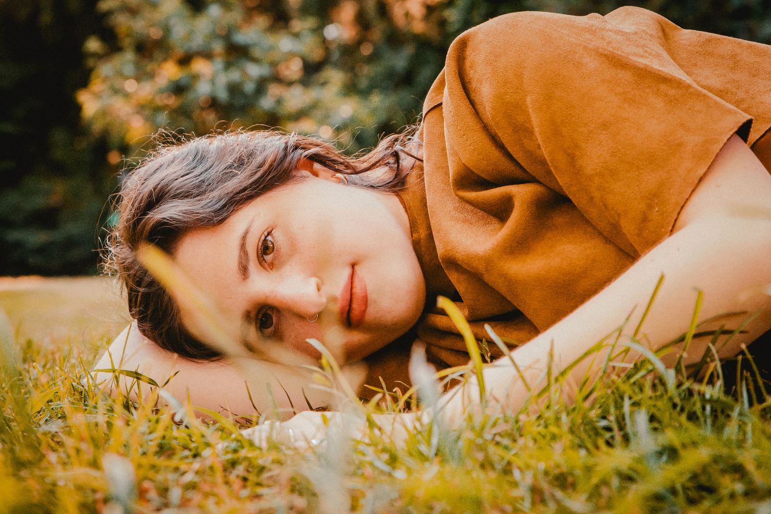 Prospect park portrait session at golden hour. Close up portrait of woman lying in the grass with trees in the background.