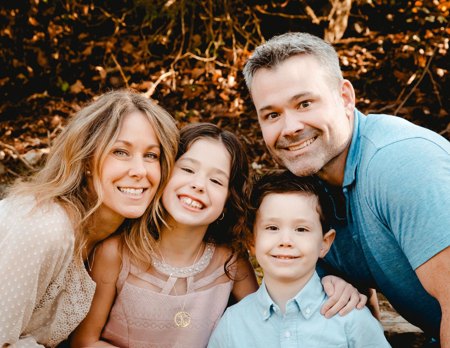 A family portrait in Ardsley, NY. Everyone smiles and laughs while looking at the camera. Glowing sunlight & trees in the background