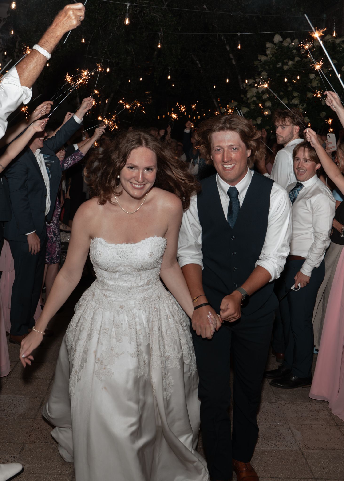 Wedding reception dance floor filled with guests celebrating under twinkling lights.