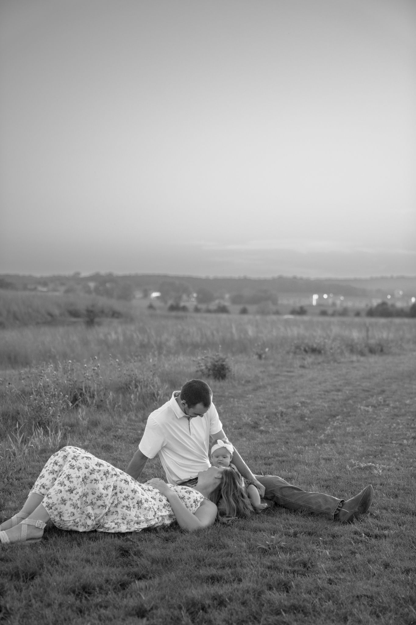 Black and white photo of couple relaxing in a meadow.