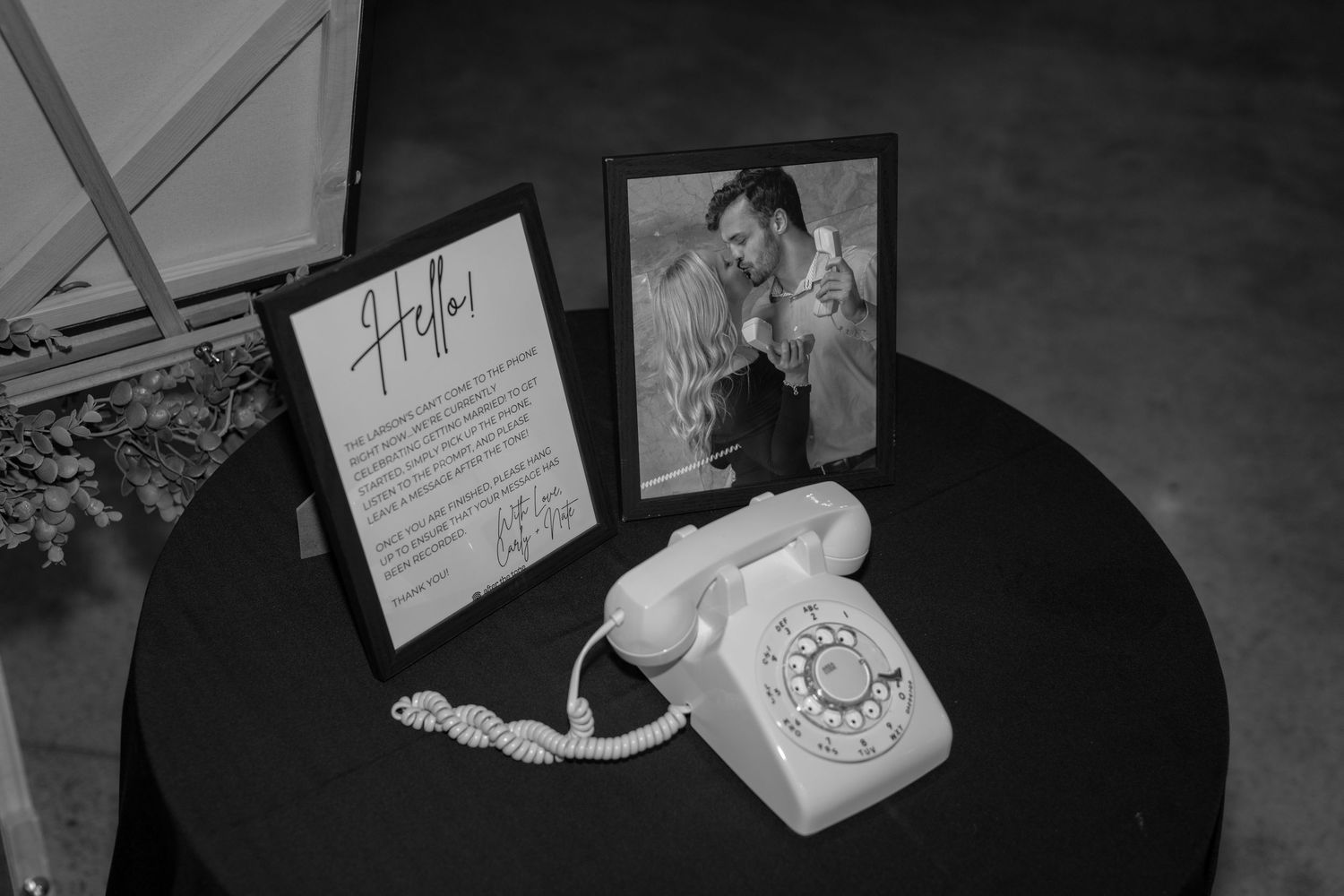 Vintage rotary phone and framed wedding details displayed on round table.