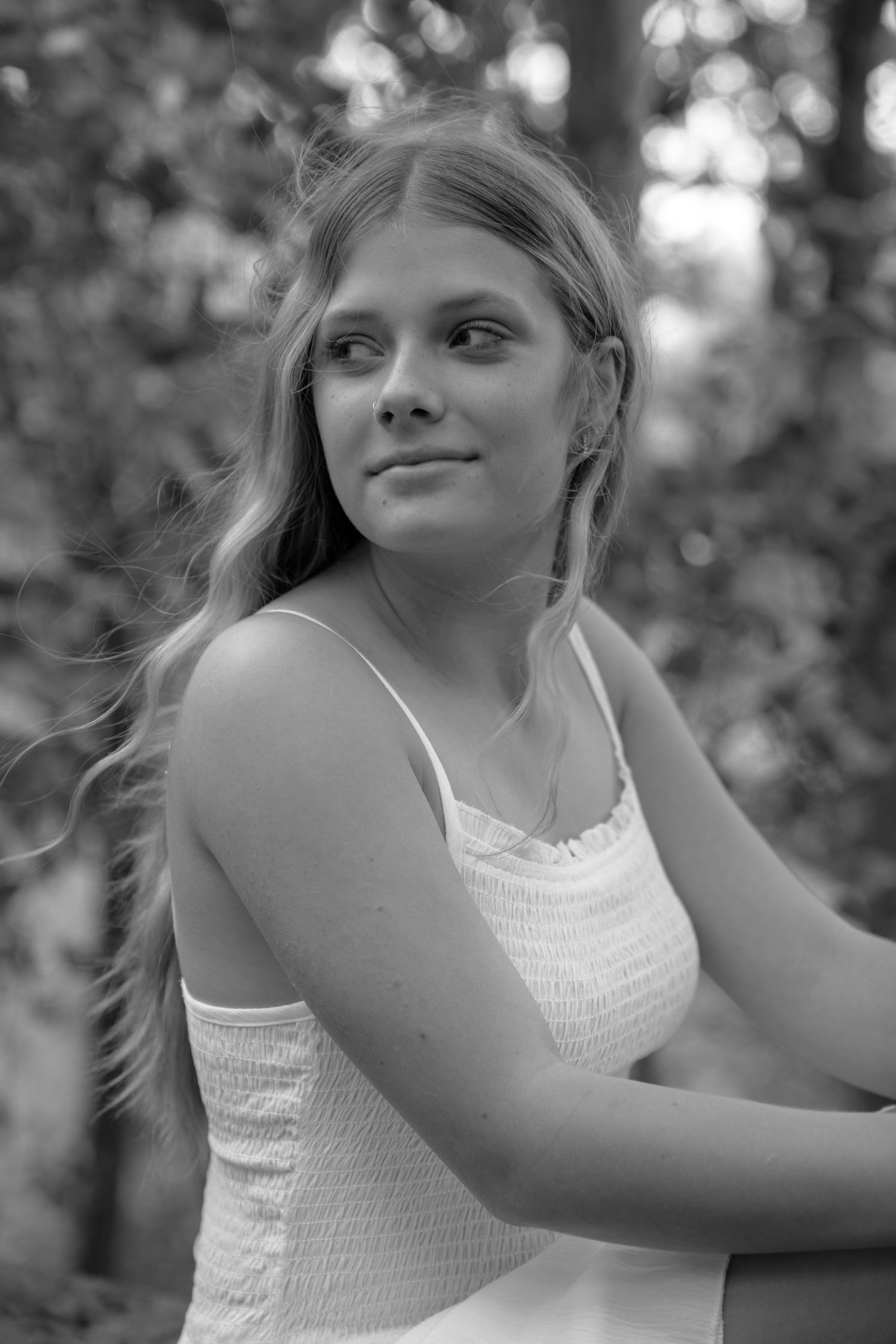 Black and white portrait series of someone in a white tank top outdoors.