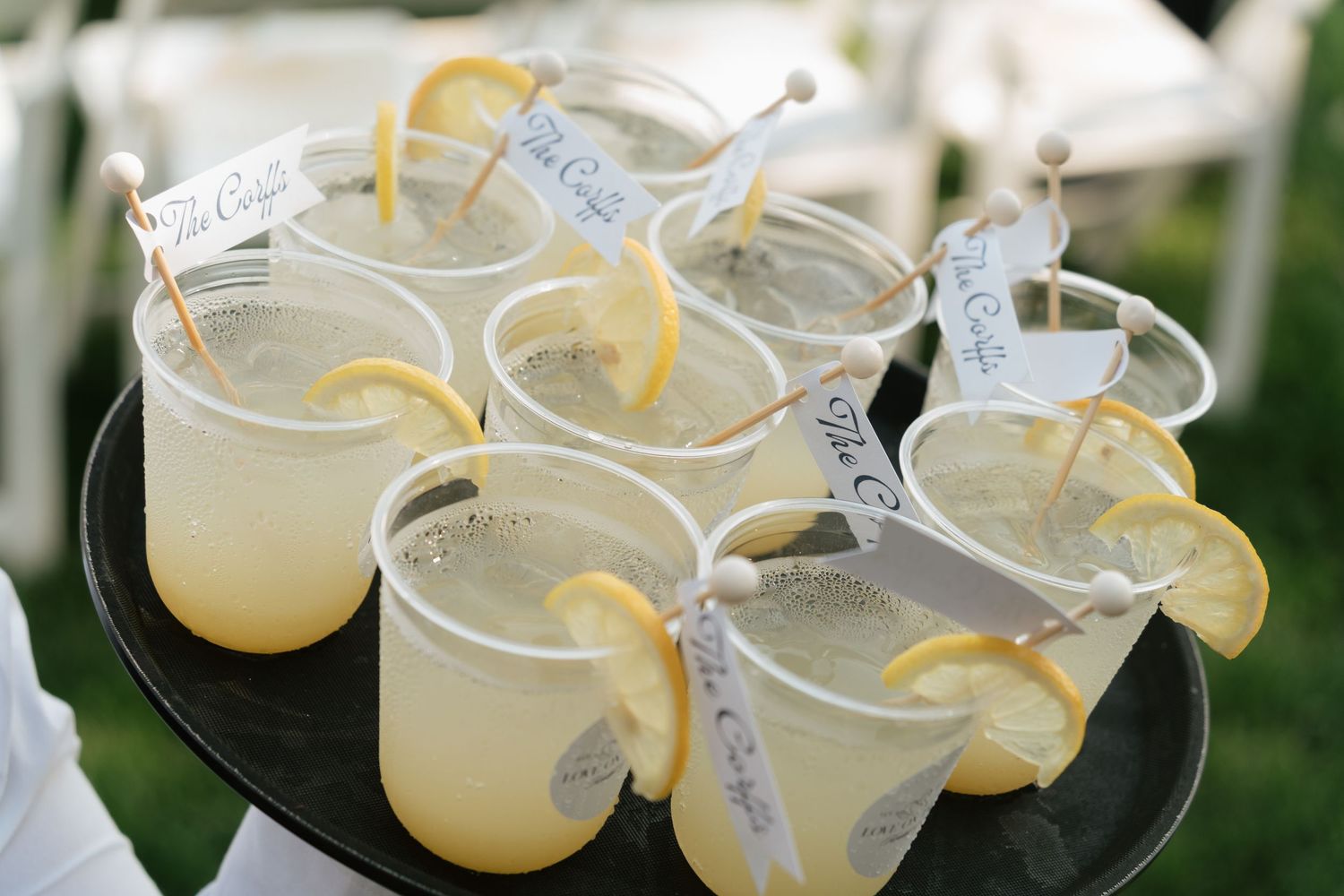 Elegant lemon wedding cocktails garnished with citrus slices and decorative flags served on a tray.