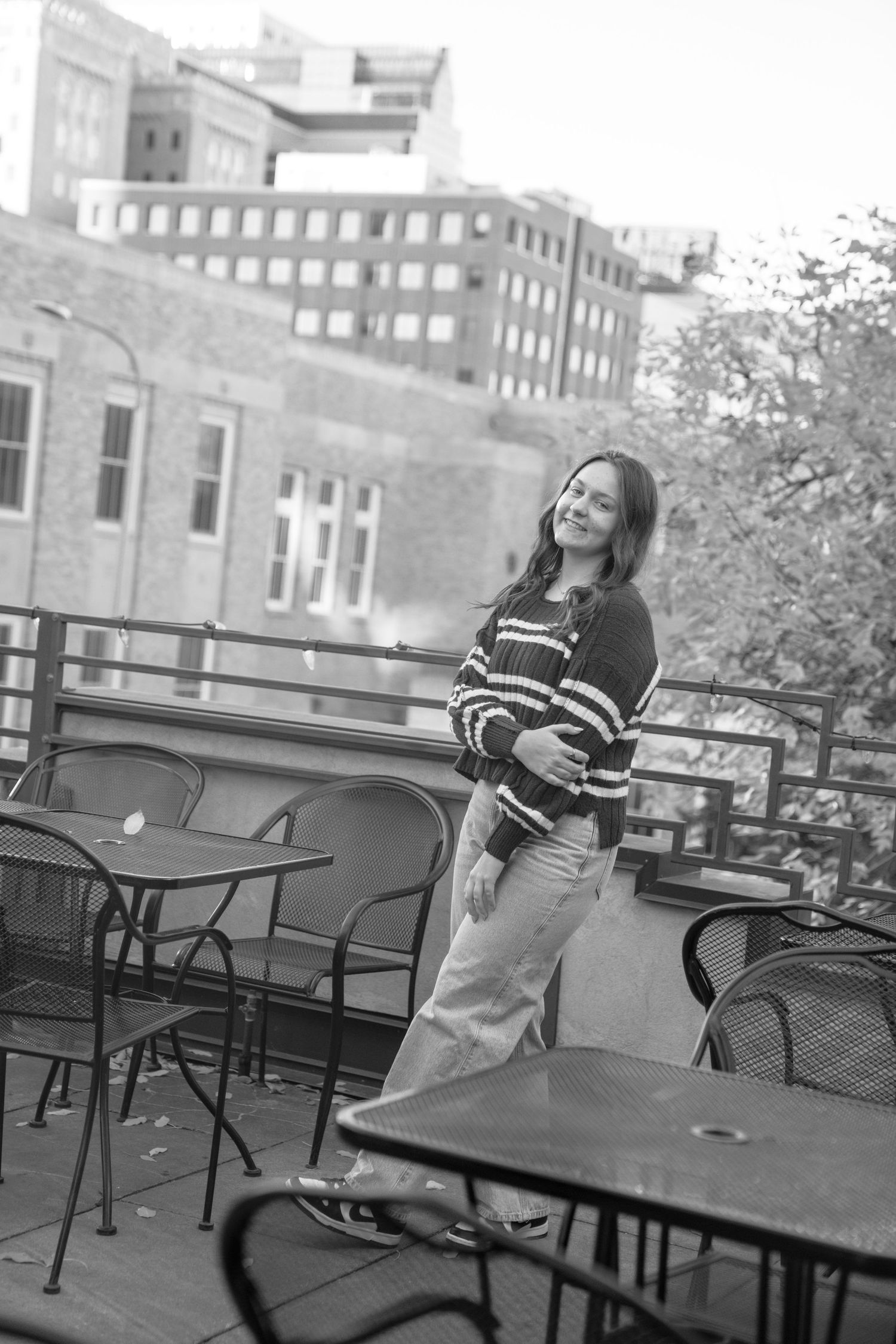 Black and white photo on a rooftop terrace with city buildings visible in the background.