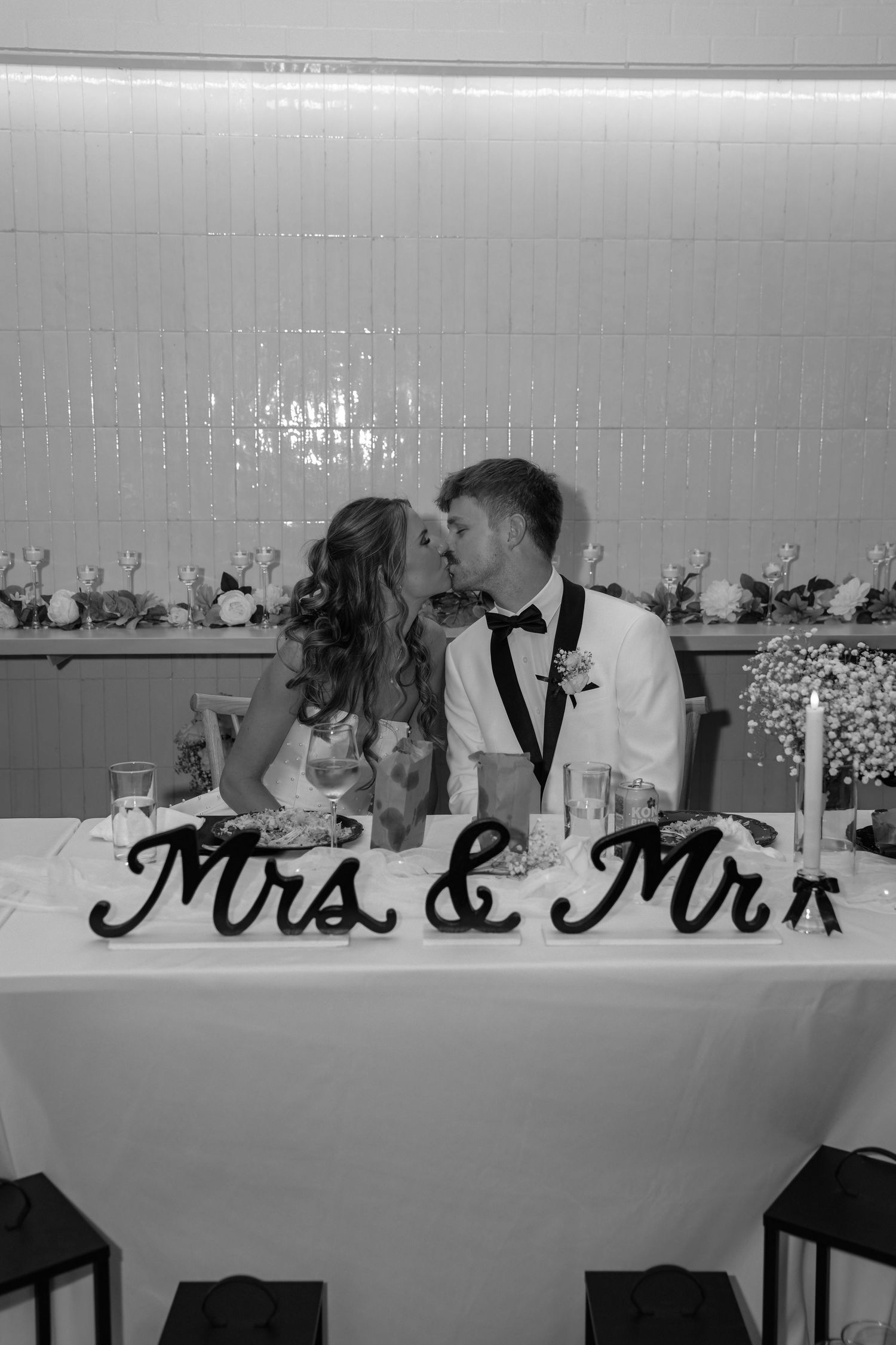 A black and white wedding reception table with 'Mrs & Mrs' signage and floral decorations in an elegant setting.