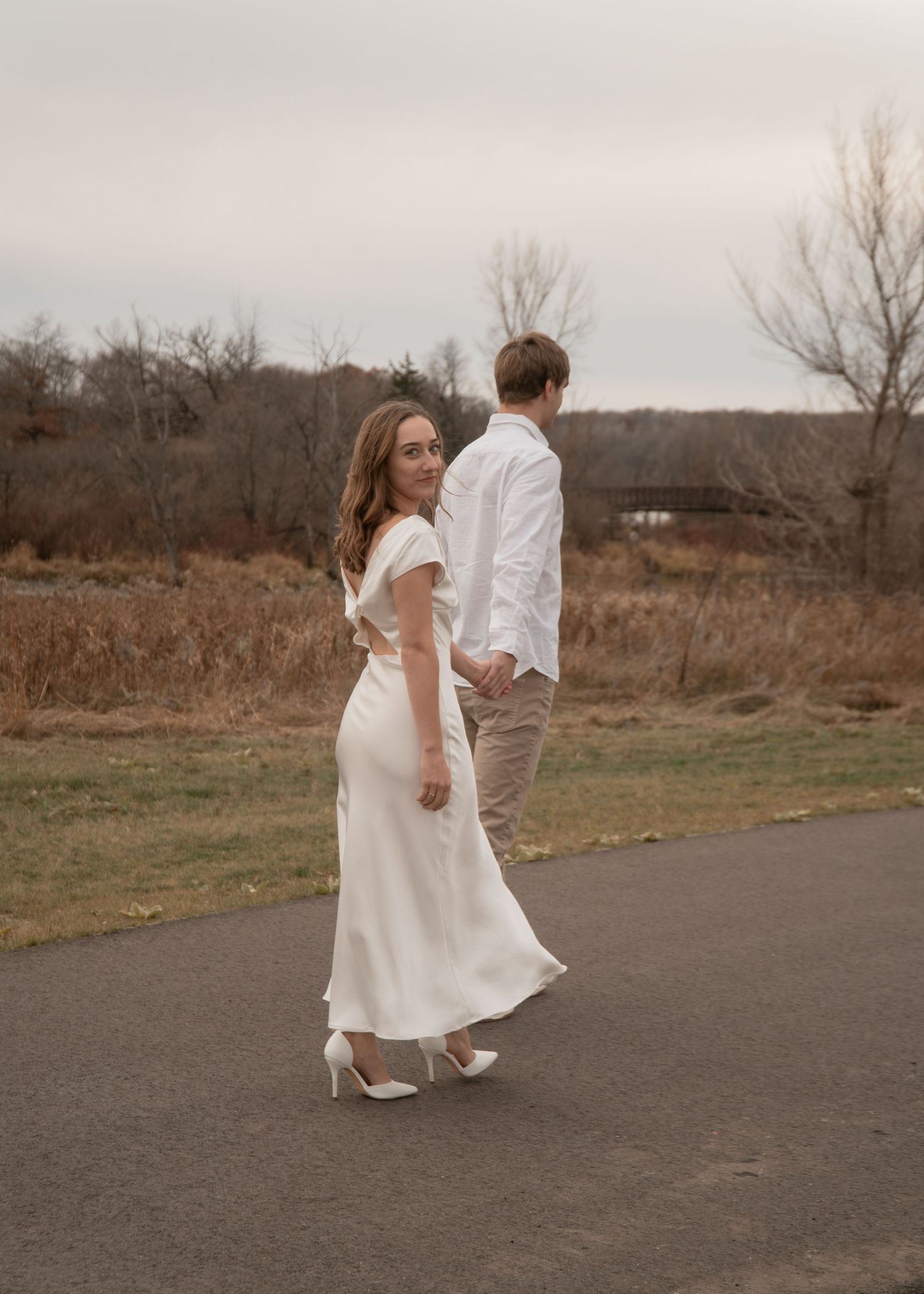 Romantic couple walking and dancing together on a paved path surrounded by autumn fields.
