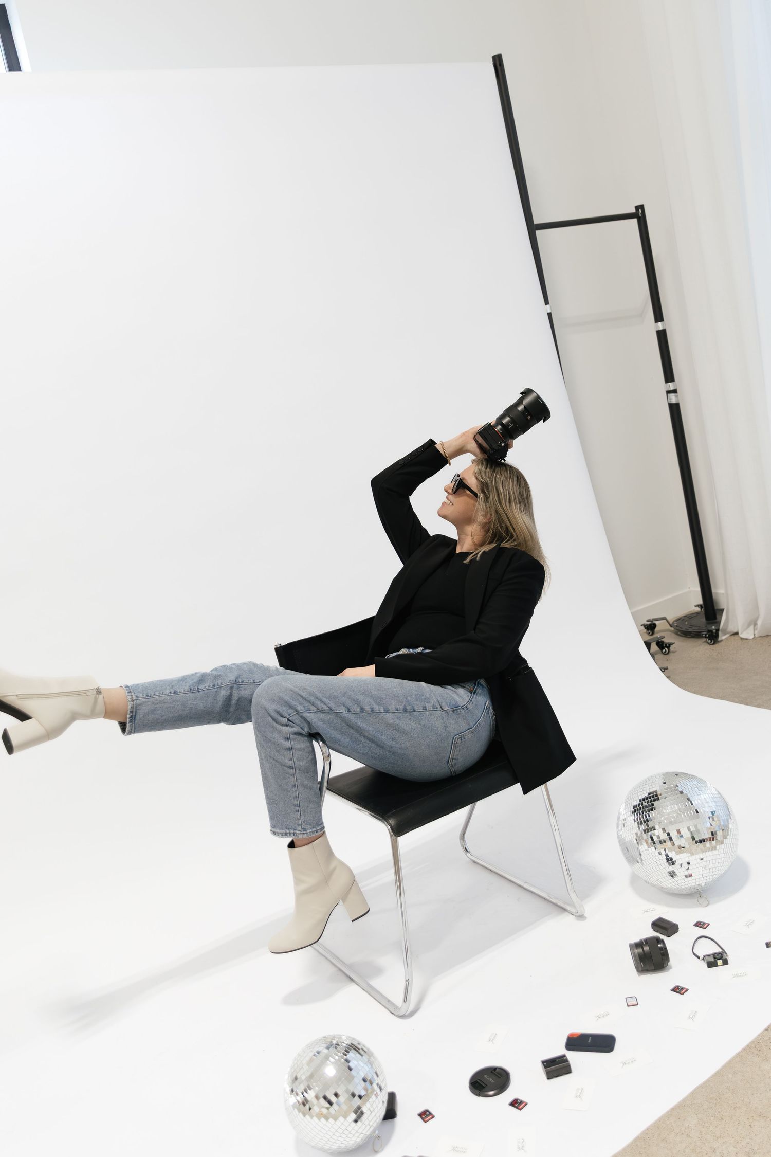 Minimalist photo series showing someone reclining in a white chair against a white background with scattered objects. Photographer near me.