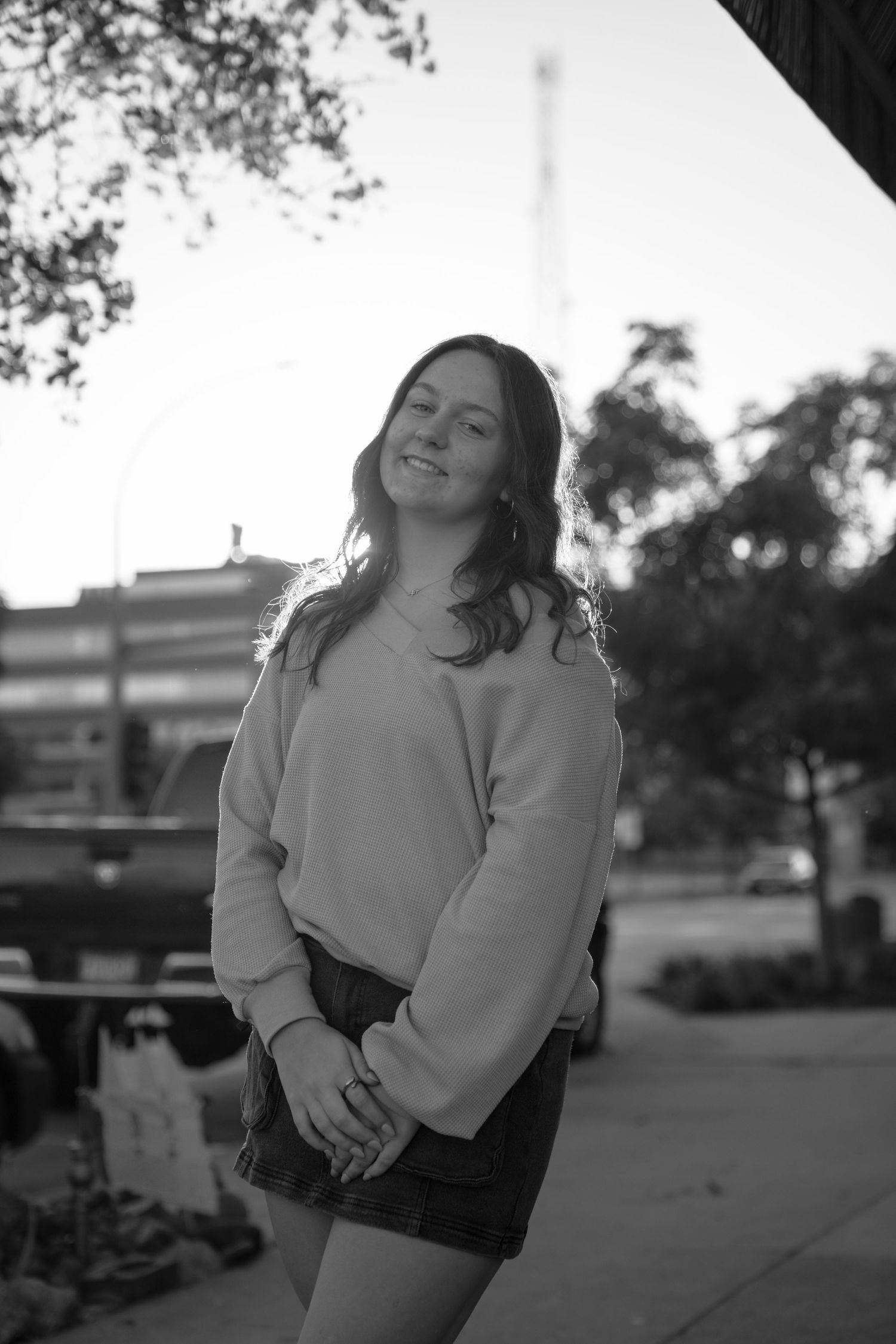 Black and white portrait featuring a relaxed pose against an outdoor urban setting.