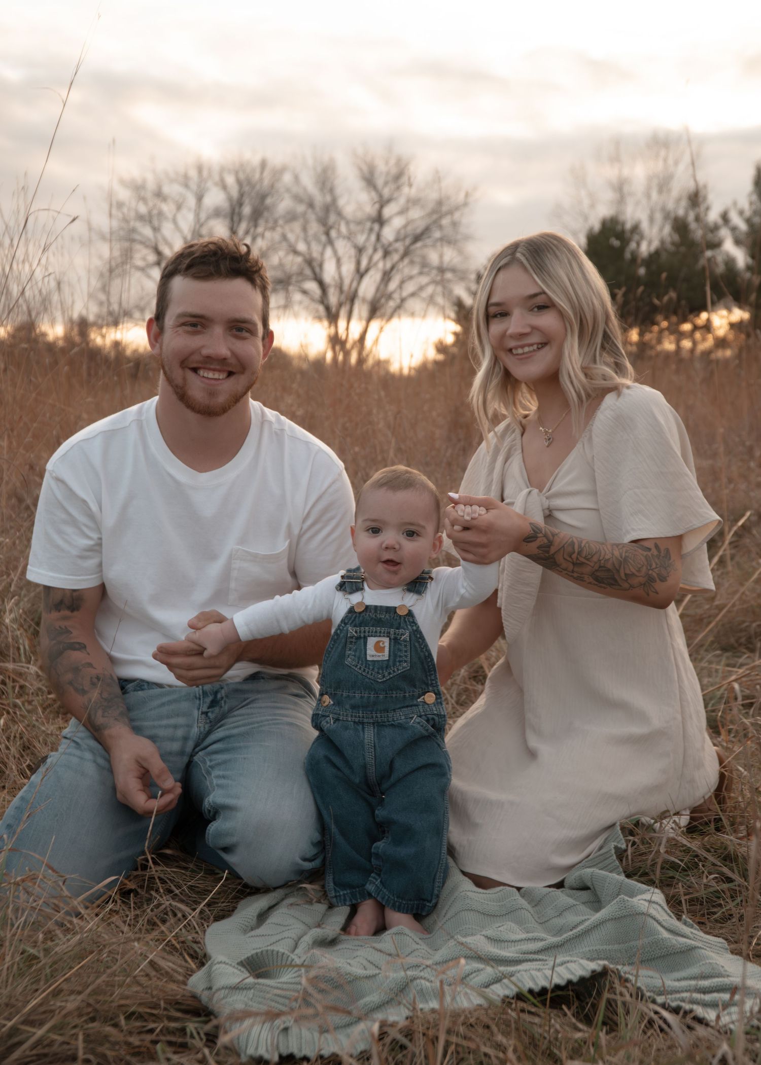 Family portrait session in a field at sunset with toddler in overalls.