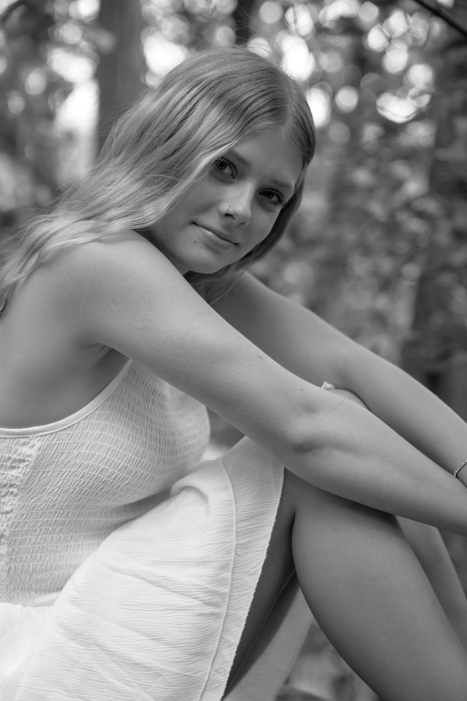 Black and white portrait series showing a person in a white summer dress against a blurred outdoor background.