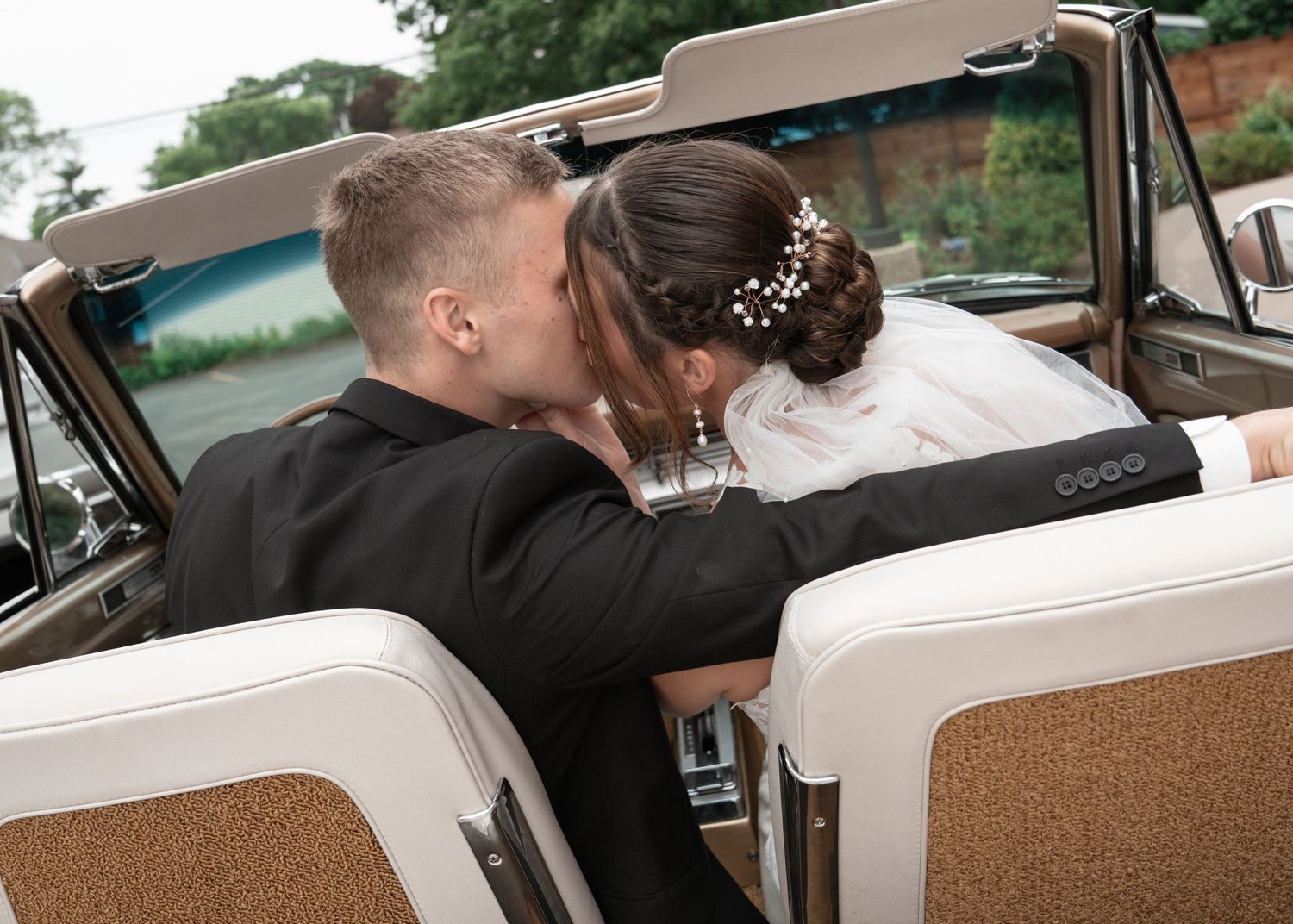 Newlyweds sitting in a vintage car with tan interior after their wedding.