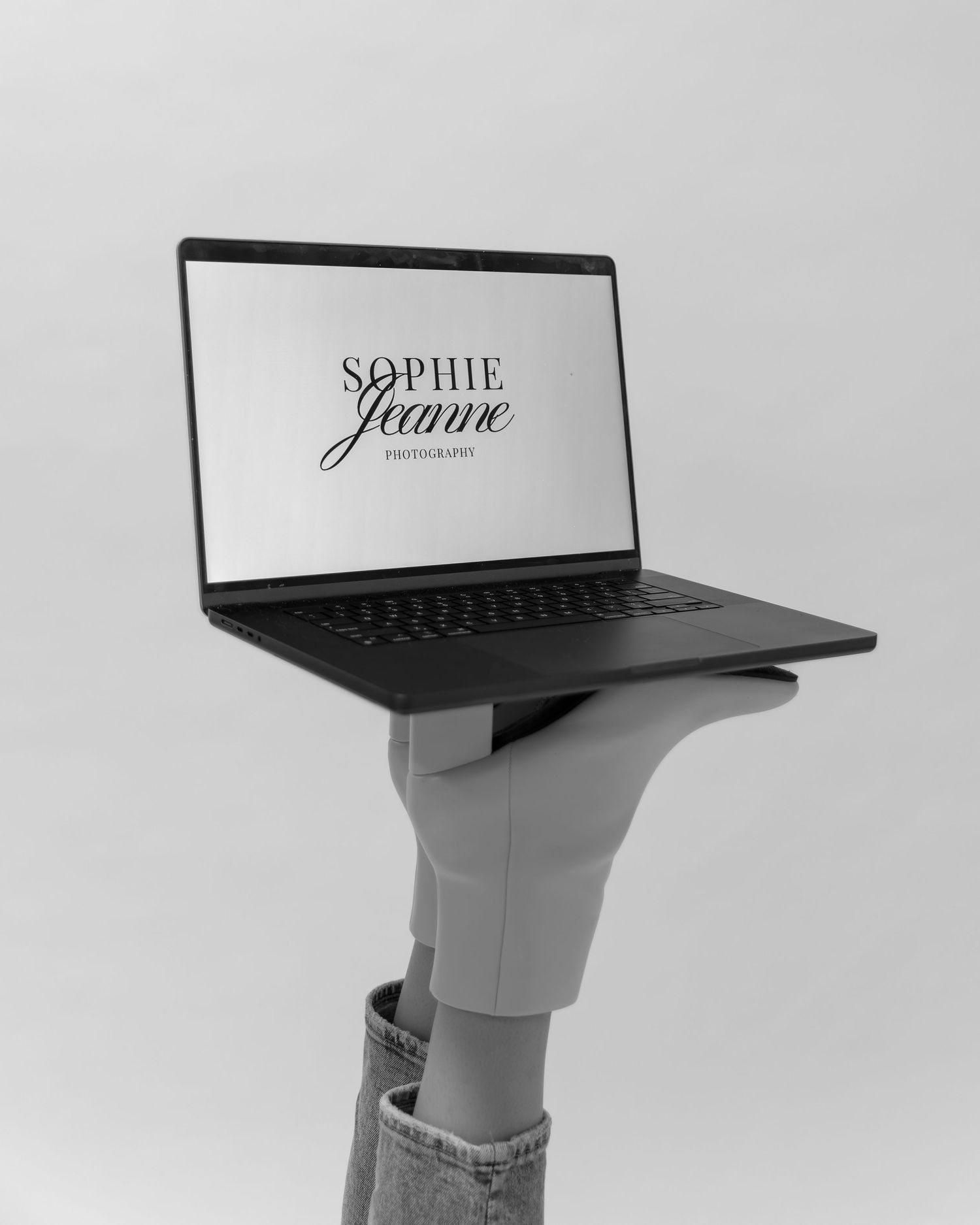 A laptop computer balances precariously on a tall white pedestal stand against a light gray background.