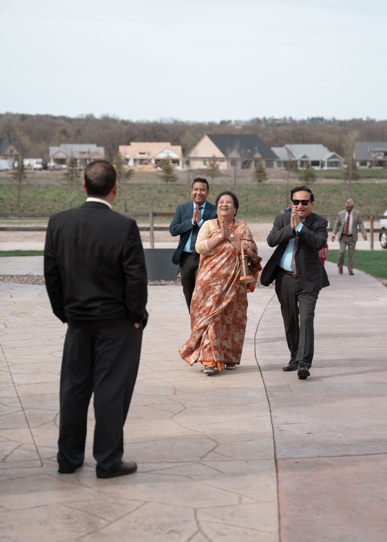 A photo shows people in cultural formal attire walking and greeting guests at a wedding. Rochester, MN wedding.