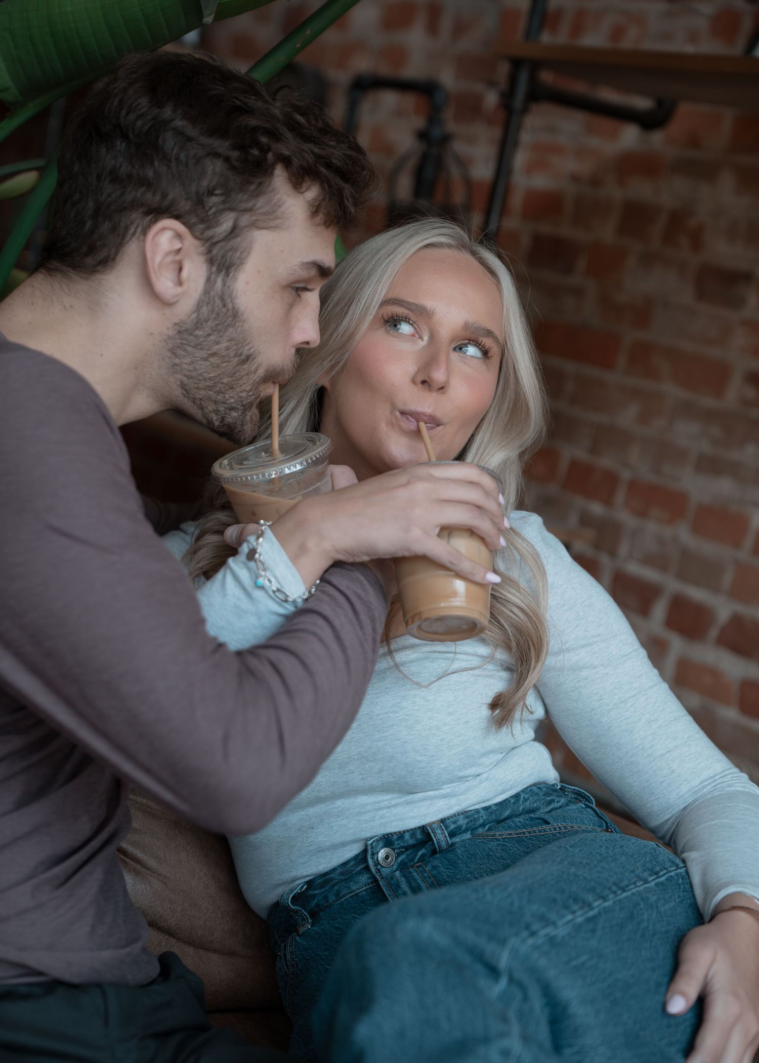 Romantic couple sharing coffee drinks and intimate moments on a leather couch.