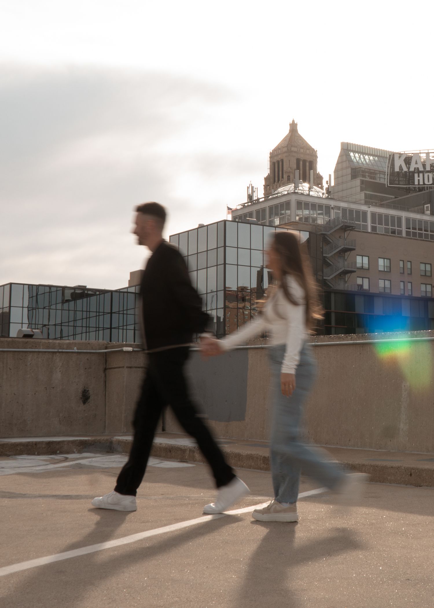 Motion blur sequence of two people dancing on a rooftop with city buildings in background.
