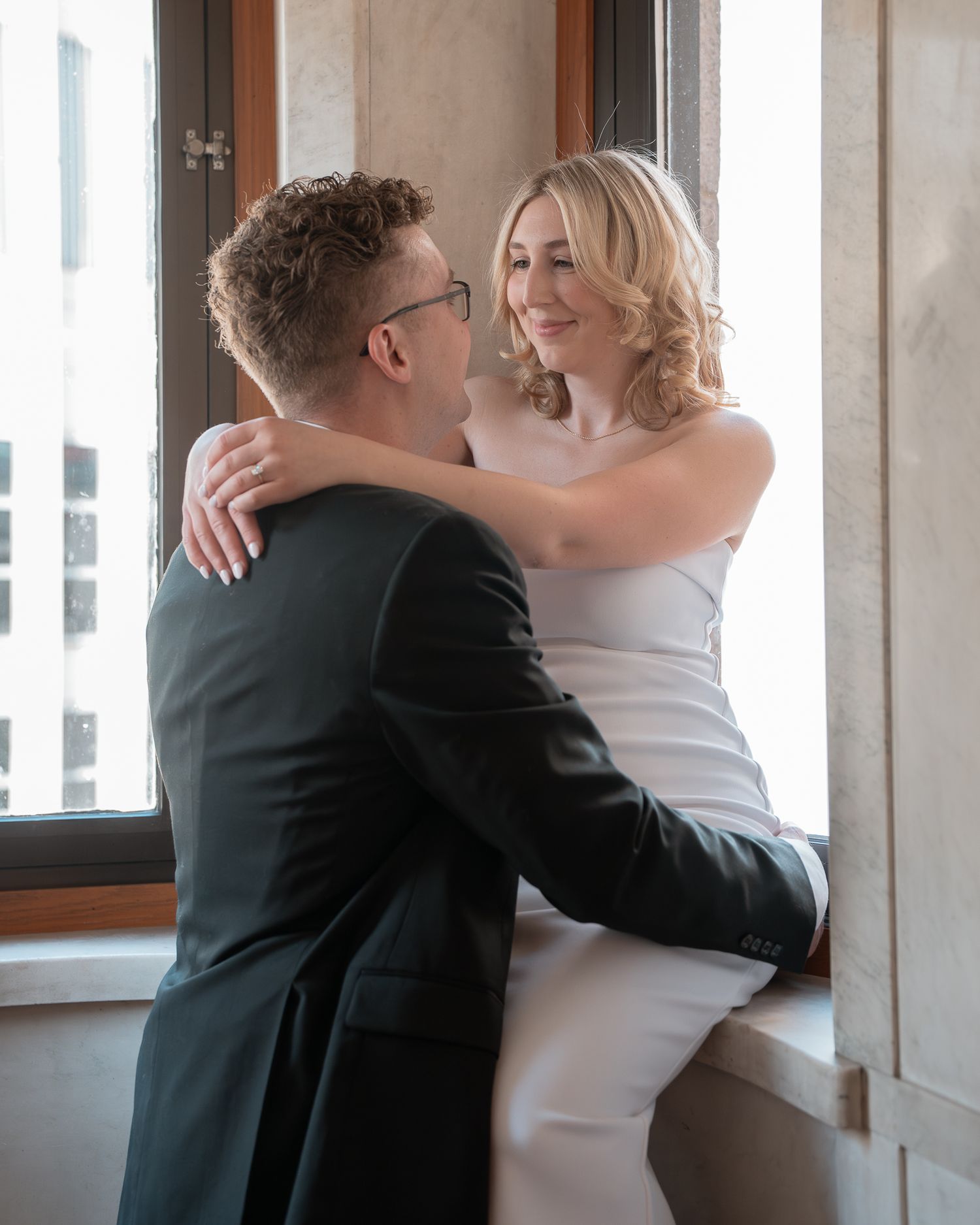Wedding couple embracing in a sequence of candid moments by a bright window.