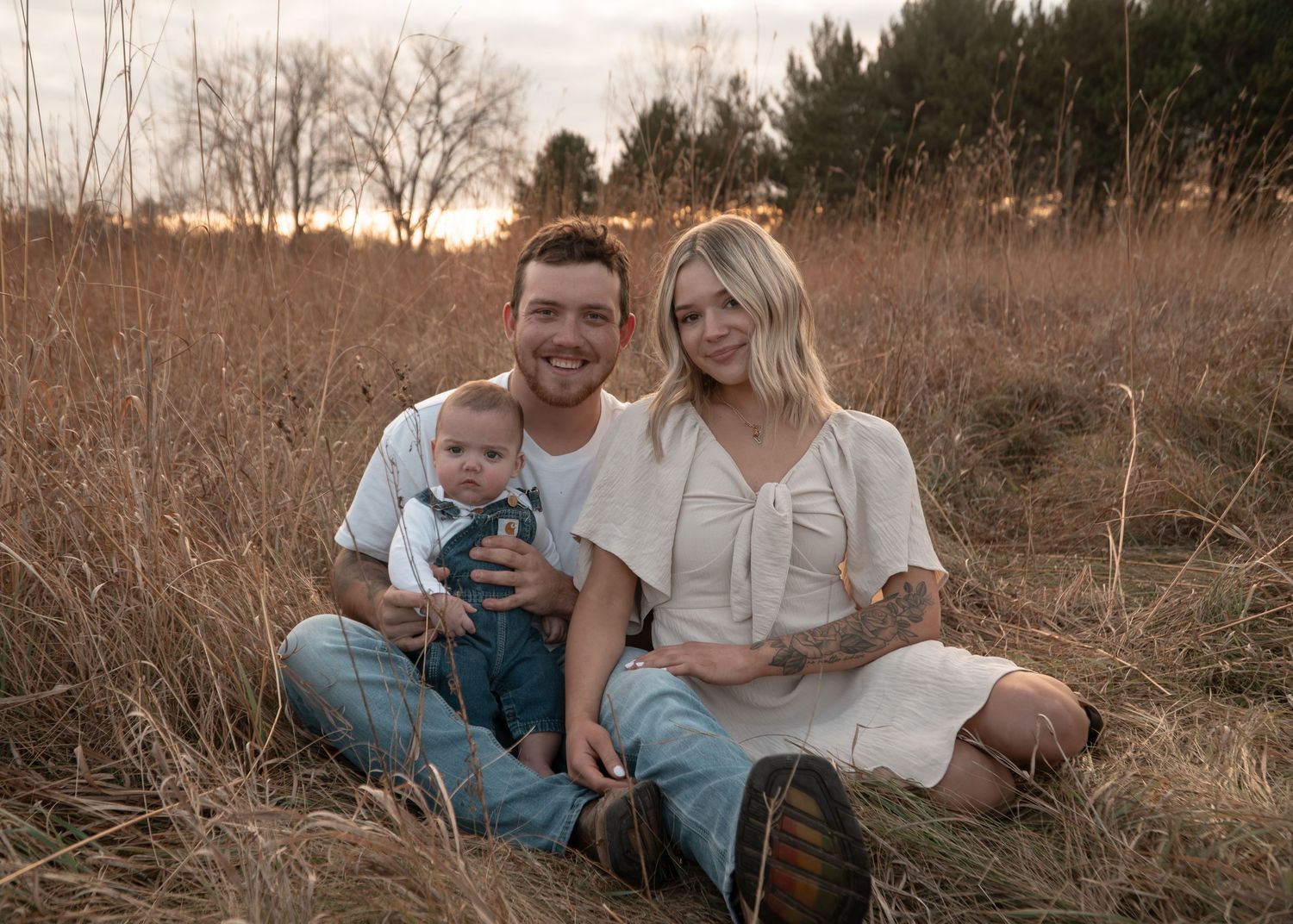 Family sitting together in a rustic field during golden hour photography session.