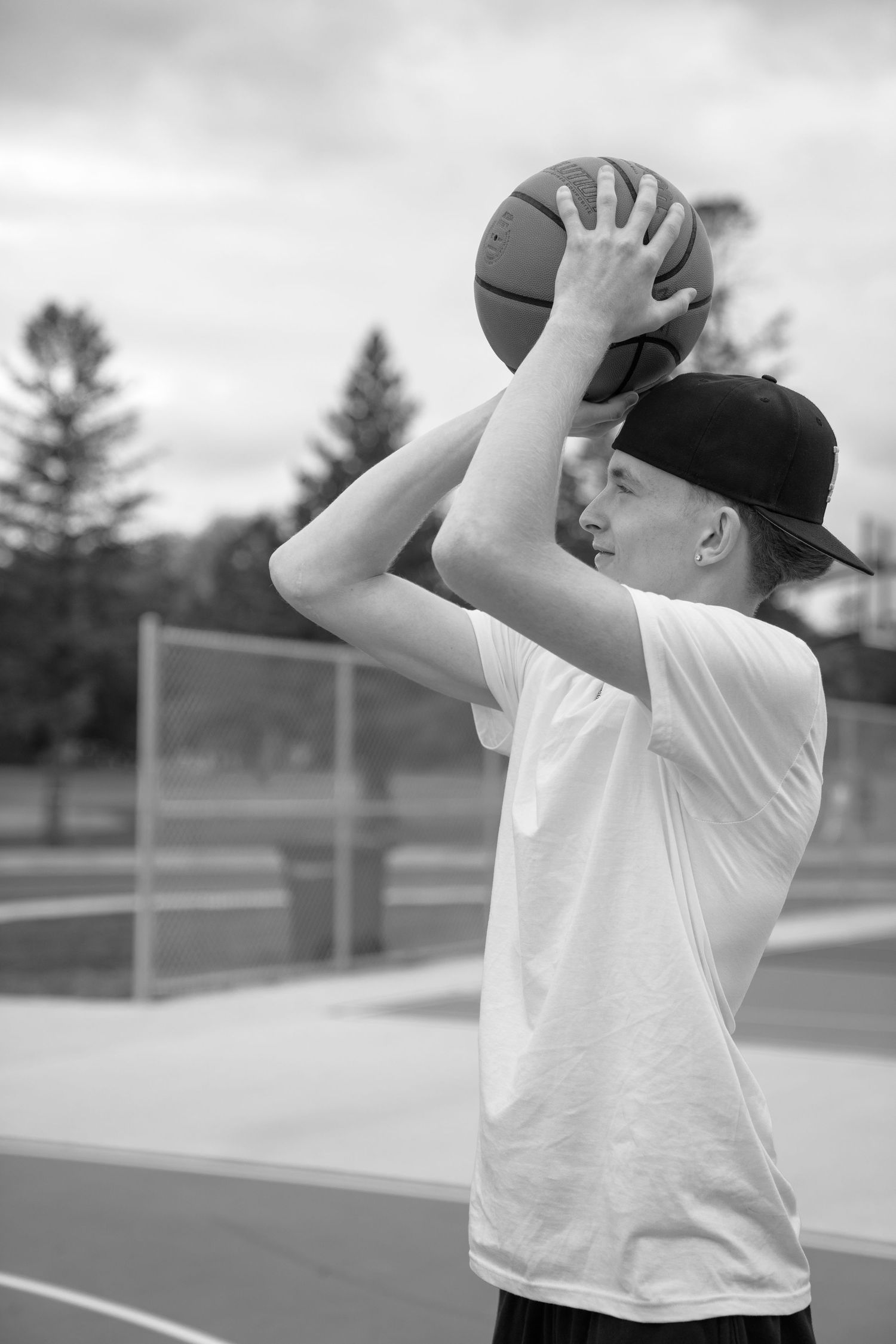 Basketball player practicing shooting form on an outdoor court.