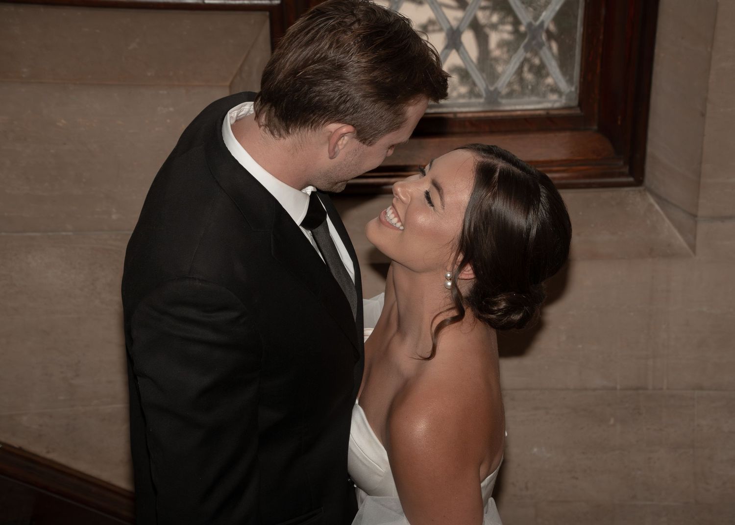 A romantic wedding couple shares a passionate kiss during their first dance in a dimly lit reception hall. Rochester, MN Plummer House.