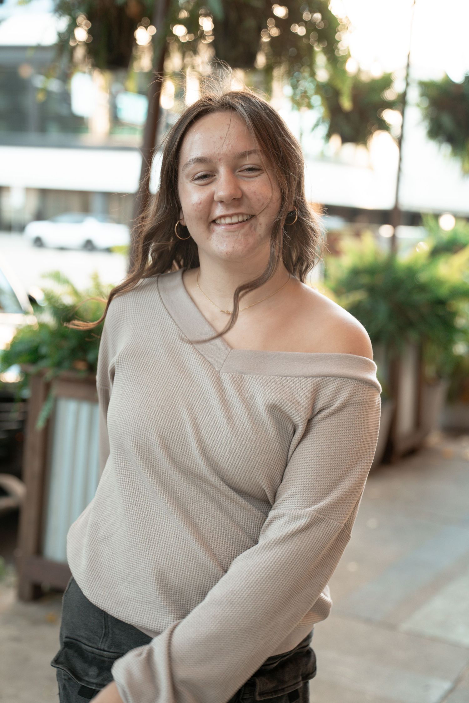 Natural light portrait featuring a casual beige off-shoulder sweater in an outdoor setting.