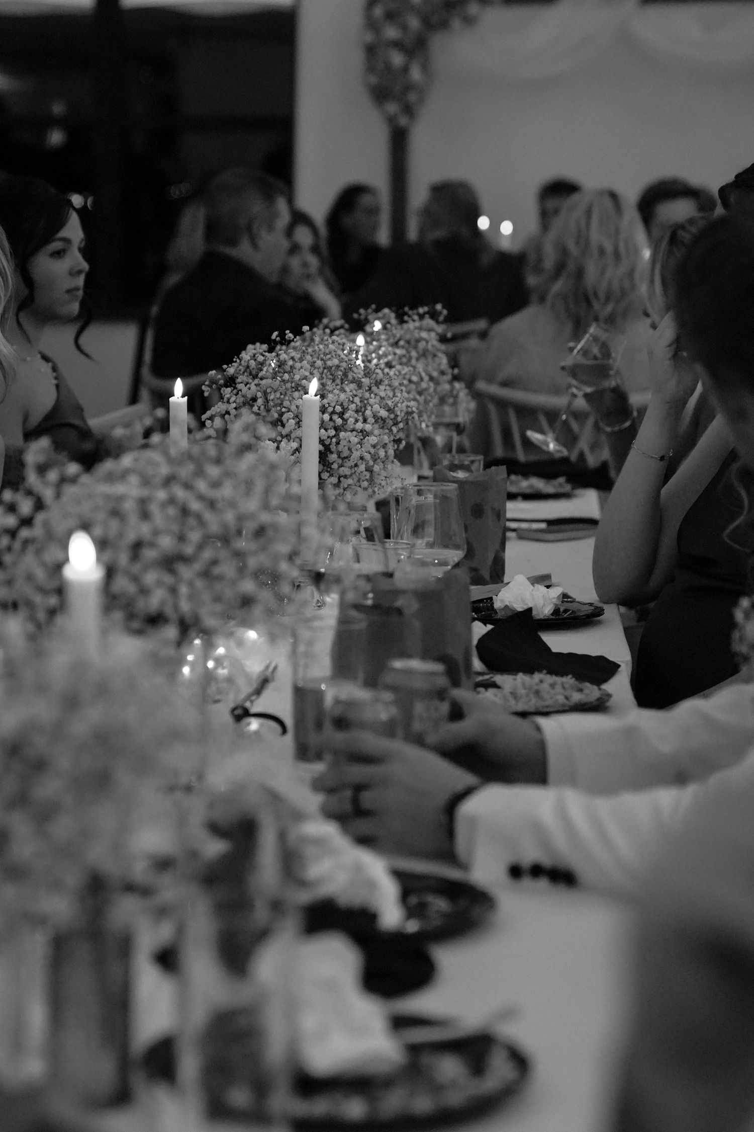 Elegant wedding reception table settings with soft candlelight and delicate baby's breath floral centerpieces.