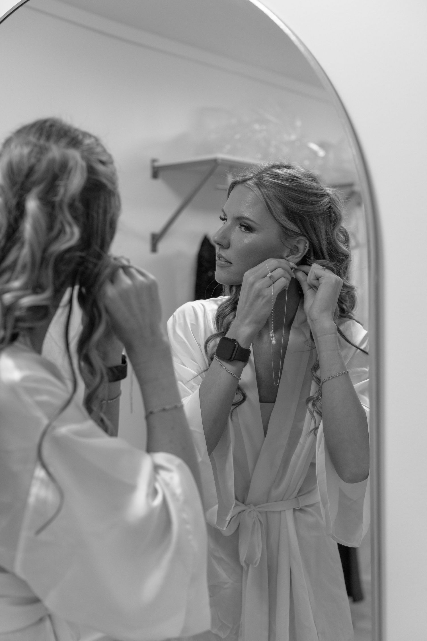 Black and white photo series showing someone applying makeup and getting ready in front of a bathroom mirror.