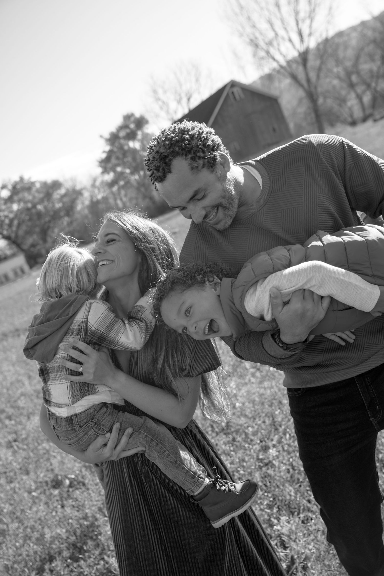 A joyful black and white family portrait showing playful interaction outdoors.