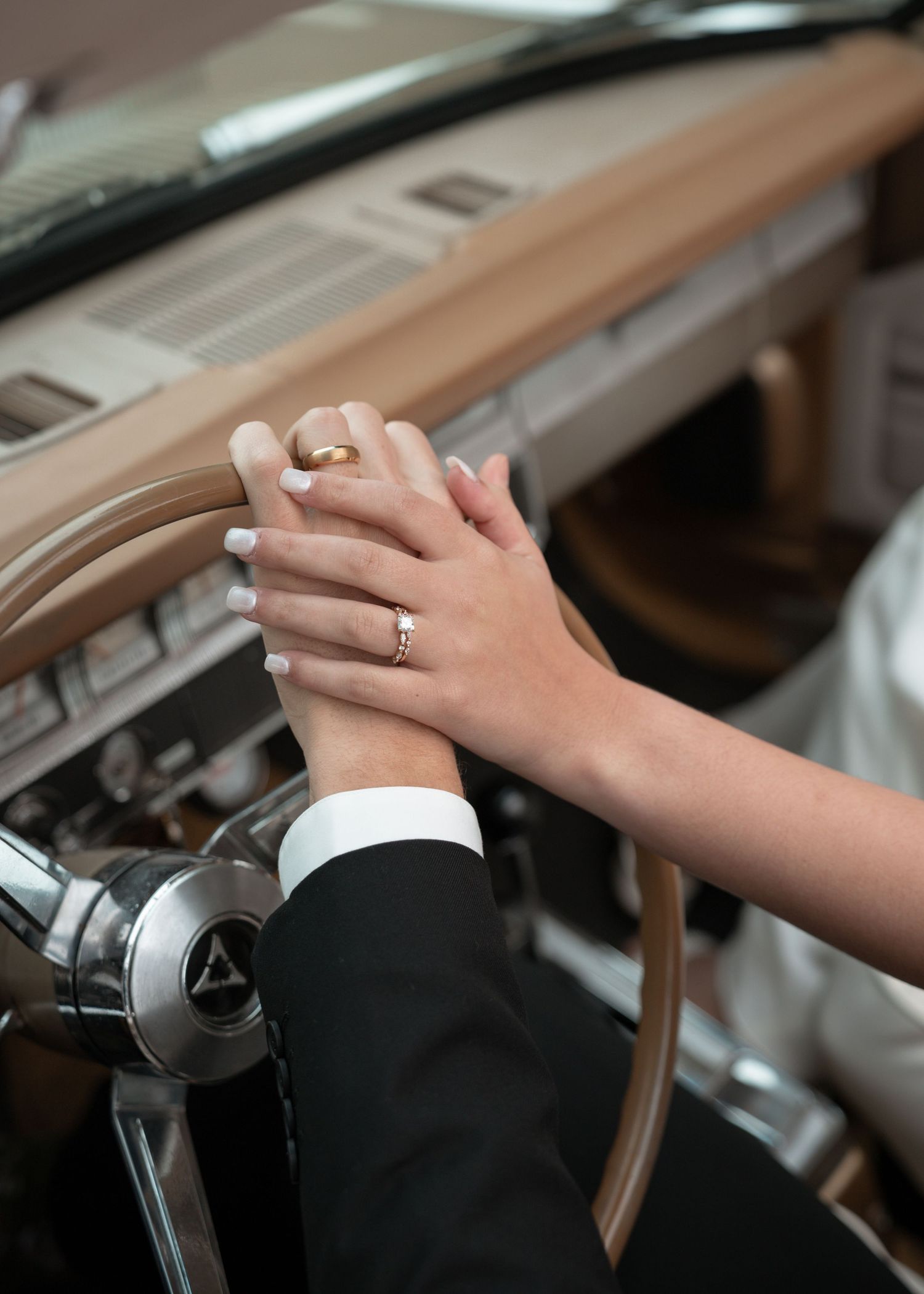 Close up of hands clasped together showing wedding rings during a ceremony.