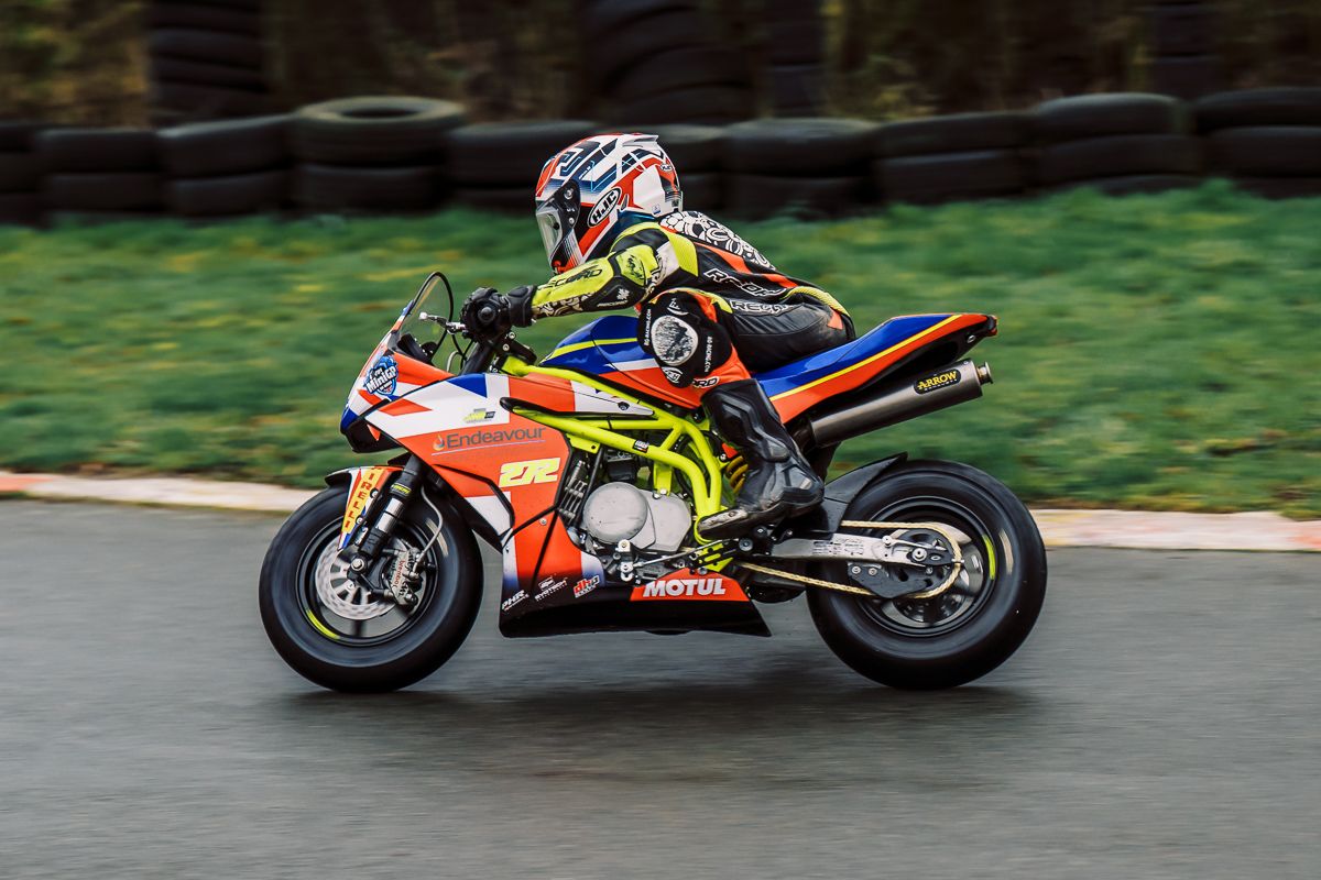 Racing motorcycles speeding through a green racetrack during competition.