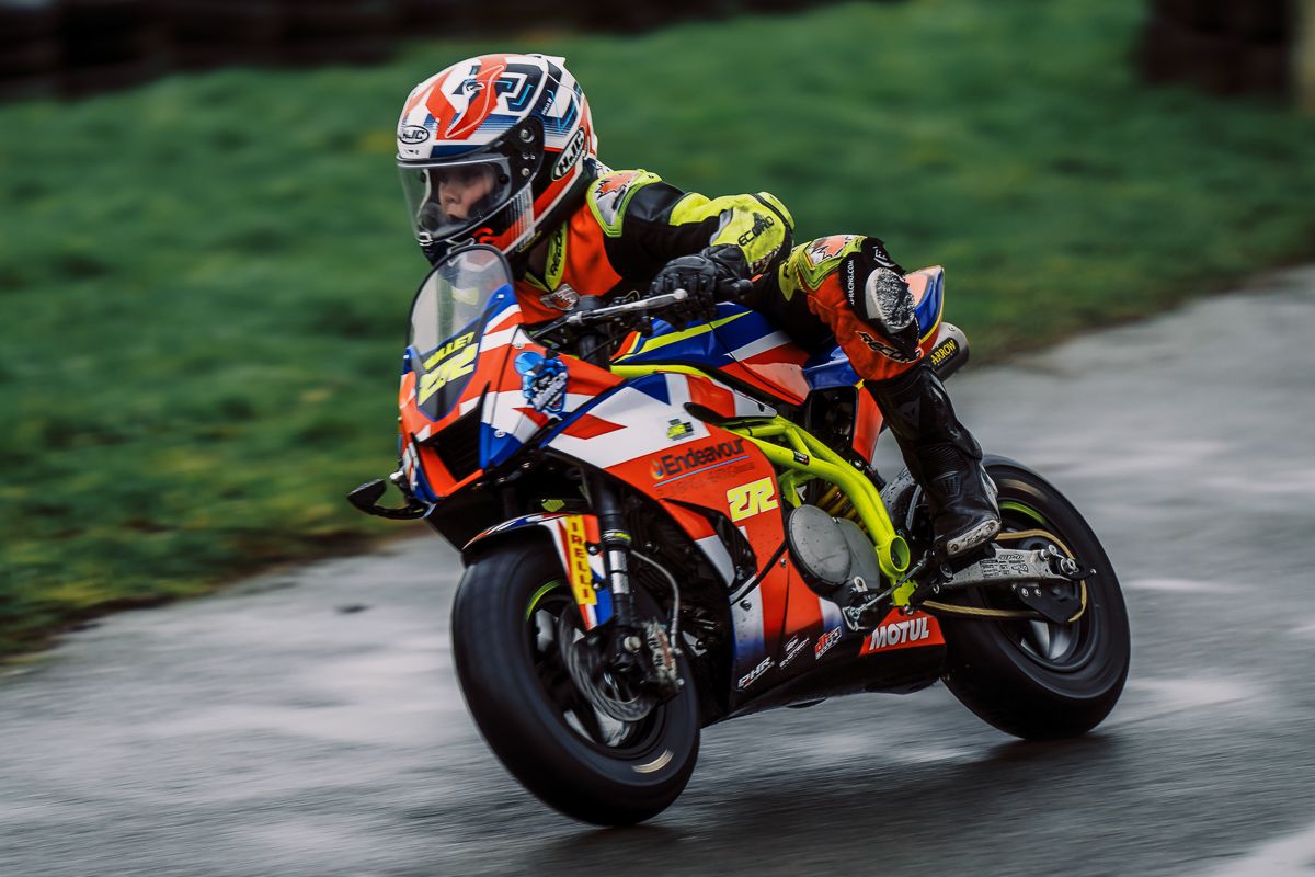 Multiple motorcycles racing on a track with riders in colorful gear.