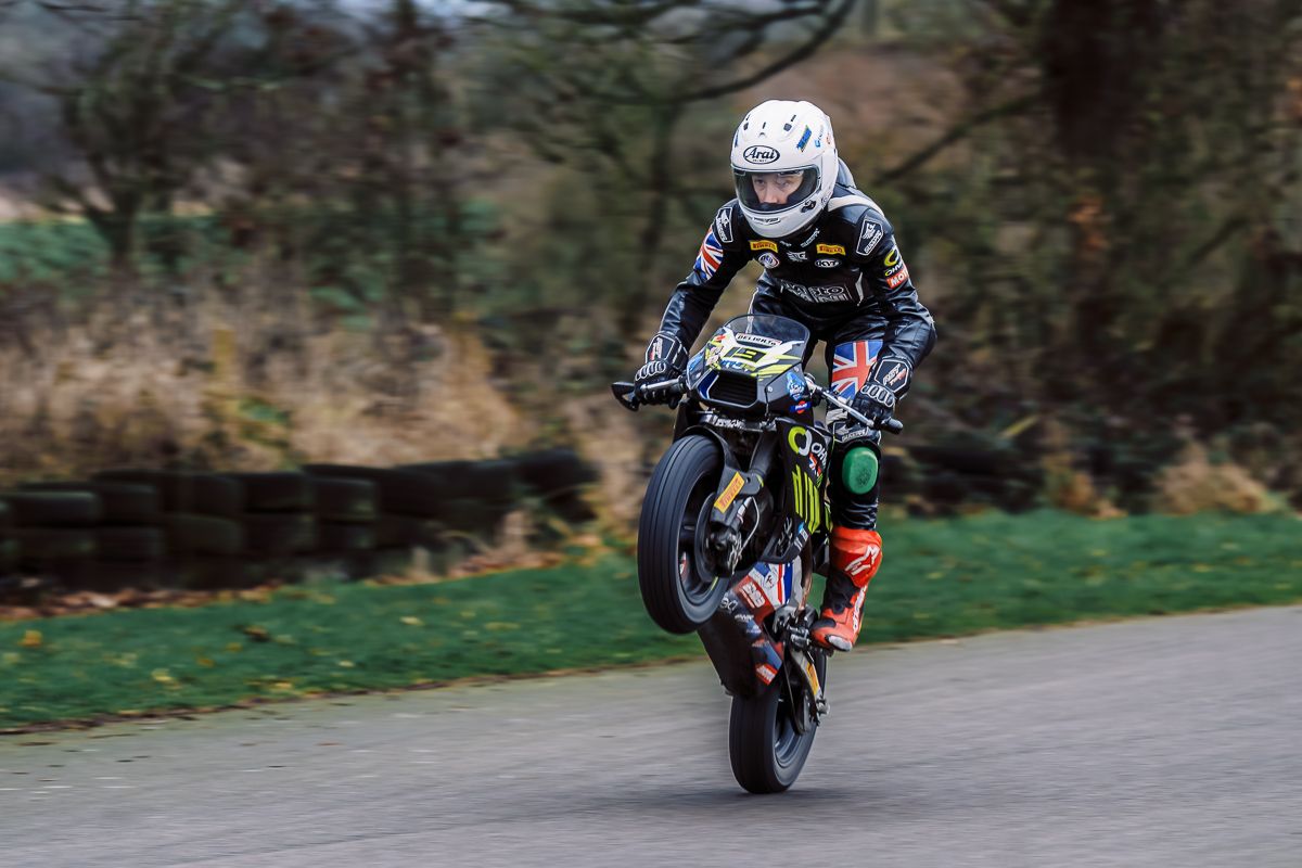 Sport bikes racing through a curved section of track surrounded by trees and grass.