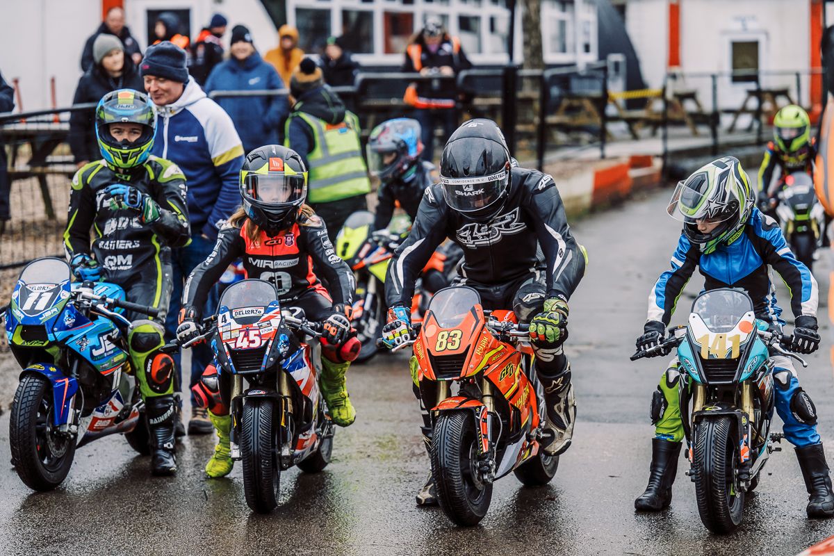 Row of sport bikes lined up at starting position on wet racing track.