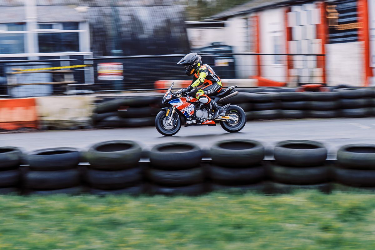 Sport bikes racing on a track with orange and white safety barriers visible in background.