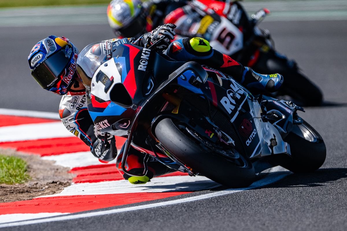 Motorcycle racers lean into sharp turns on a racing circuit during an intense competition.