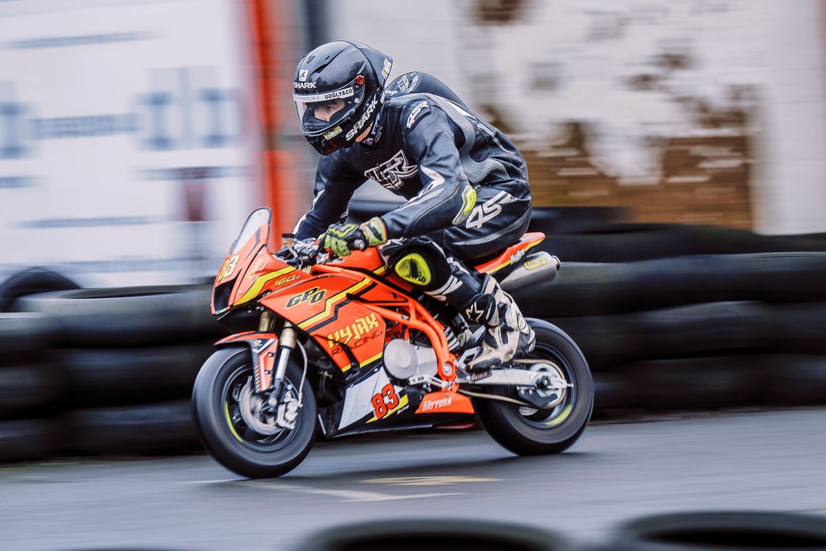 Motorcycle racer leans into a high-speed turn on a colorful sport bike during race competition.