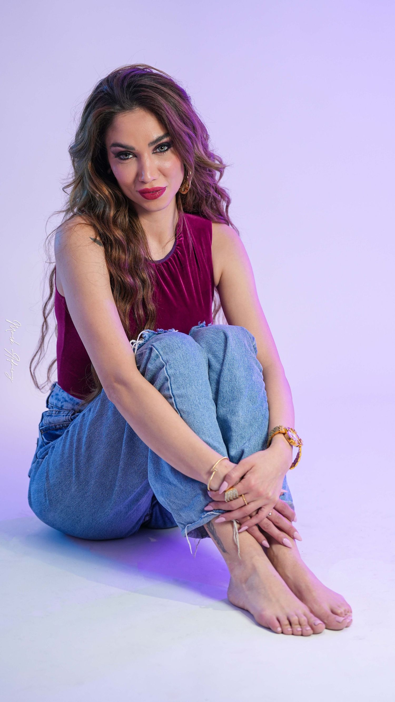 Indoor photoshoot of a model seated in a studio with soft shadows and simple violet background at CMA Productions Beirut