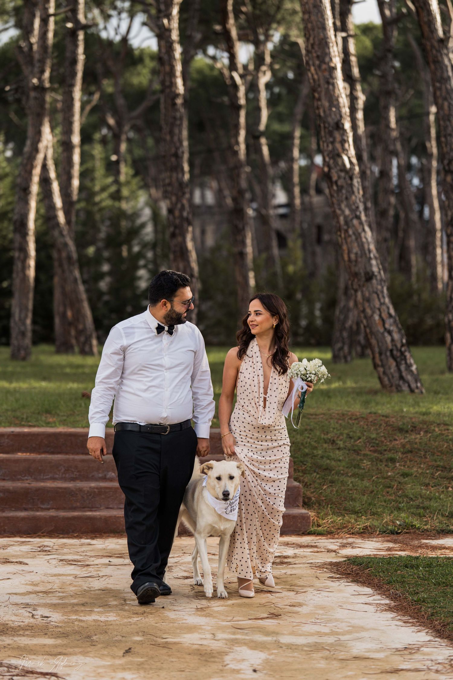 Lebanese couple walking hand in hand during pre‑wedding shoot with their beautiful dogat Riachi Winery and Distillery