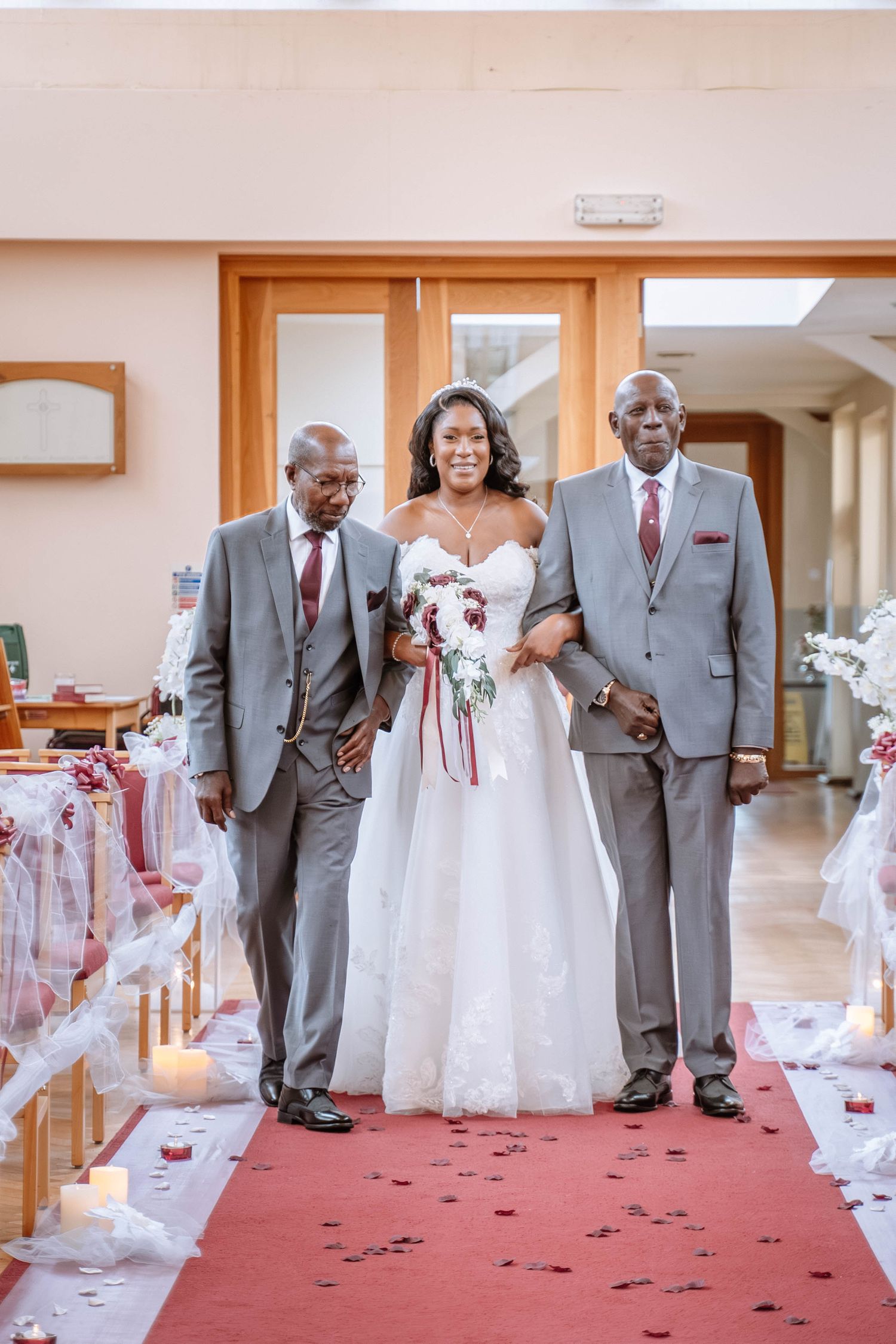 Bride walking down the aisle with her parents at a Jamaican church wedding in Birmingham