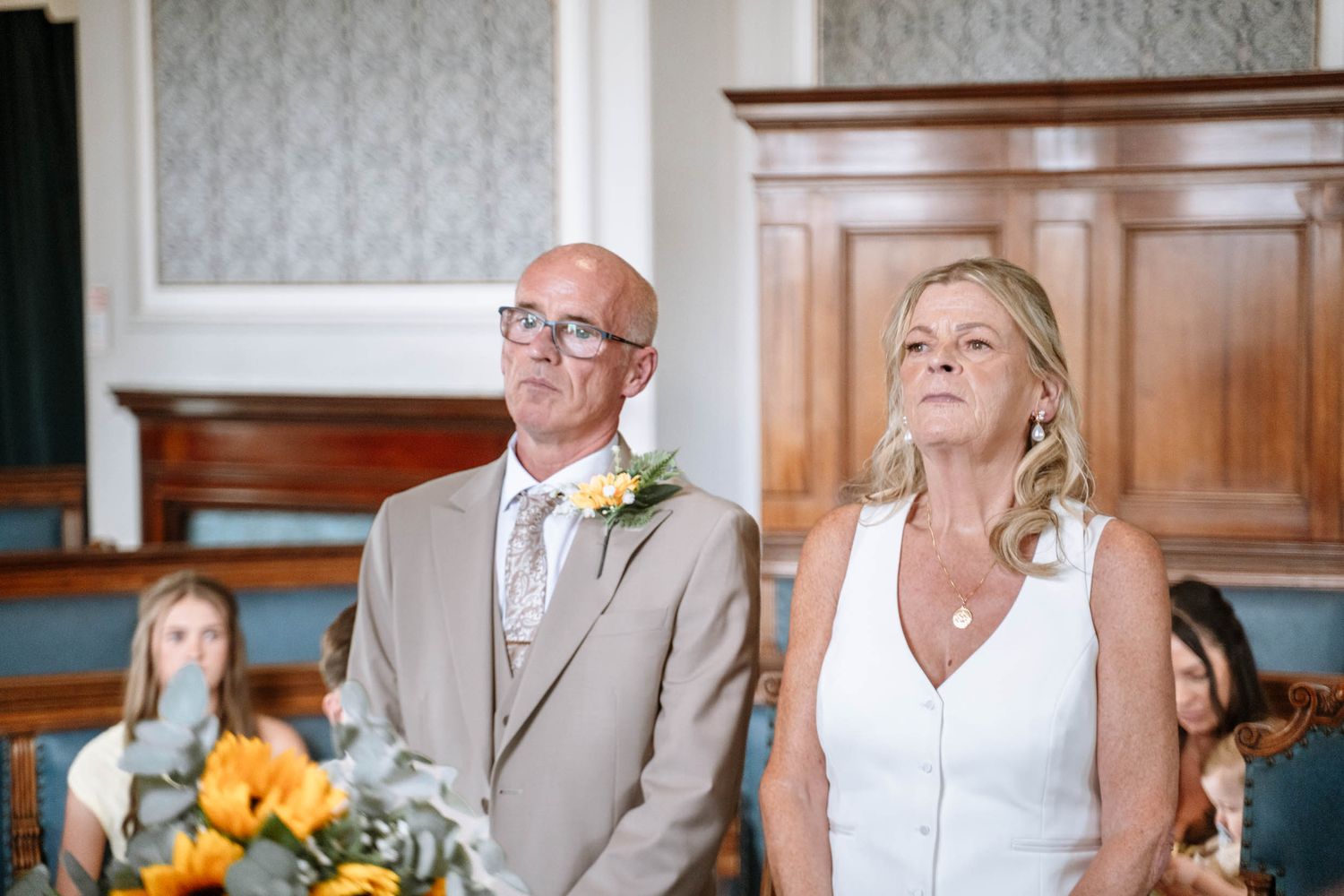 Man and woman standing together during the ceremony at Waterloo Town Hall, the woman holding a yellow bouquet