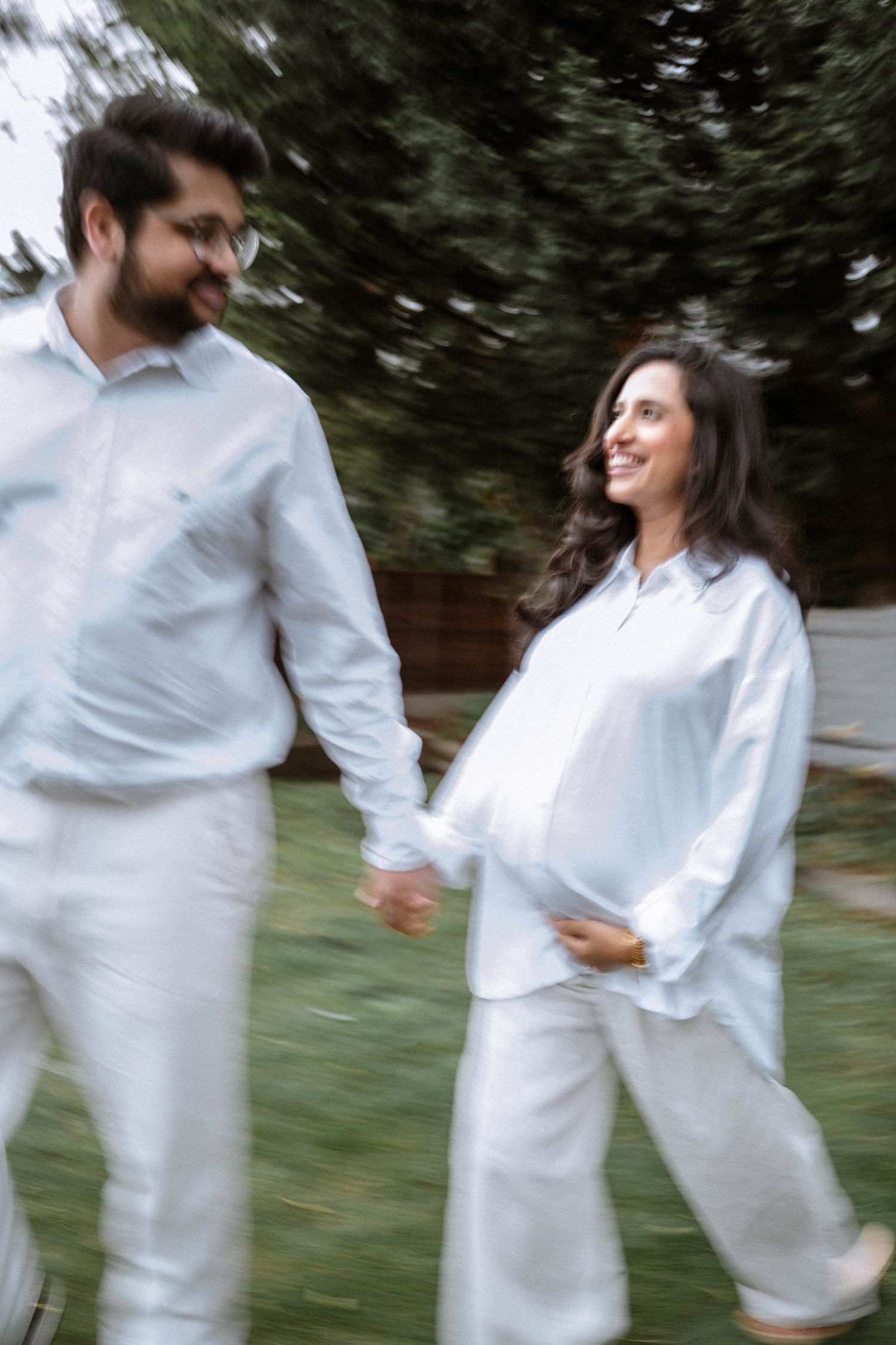 Pregnant woman walking through the garden with her partner during an at-home maternity shoot