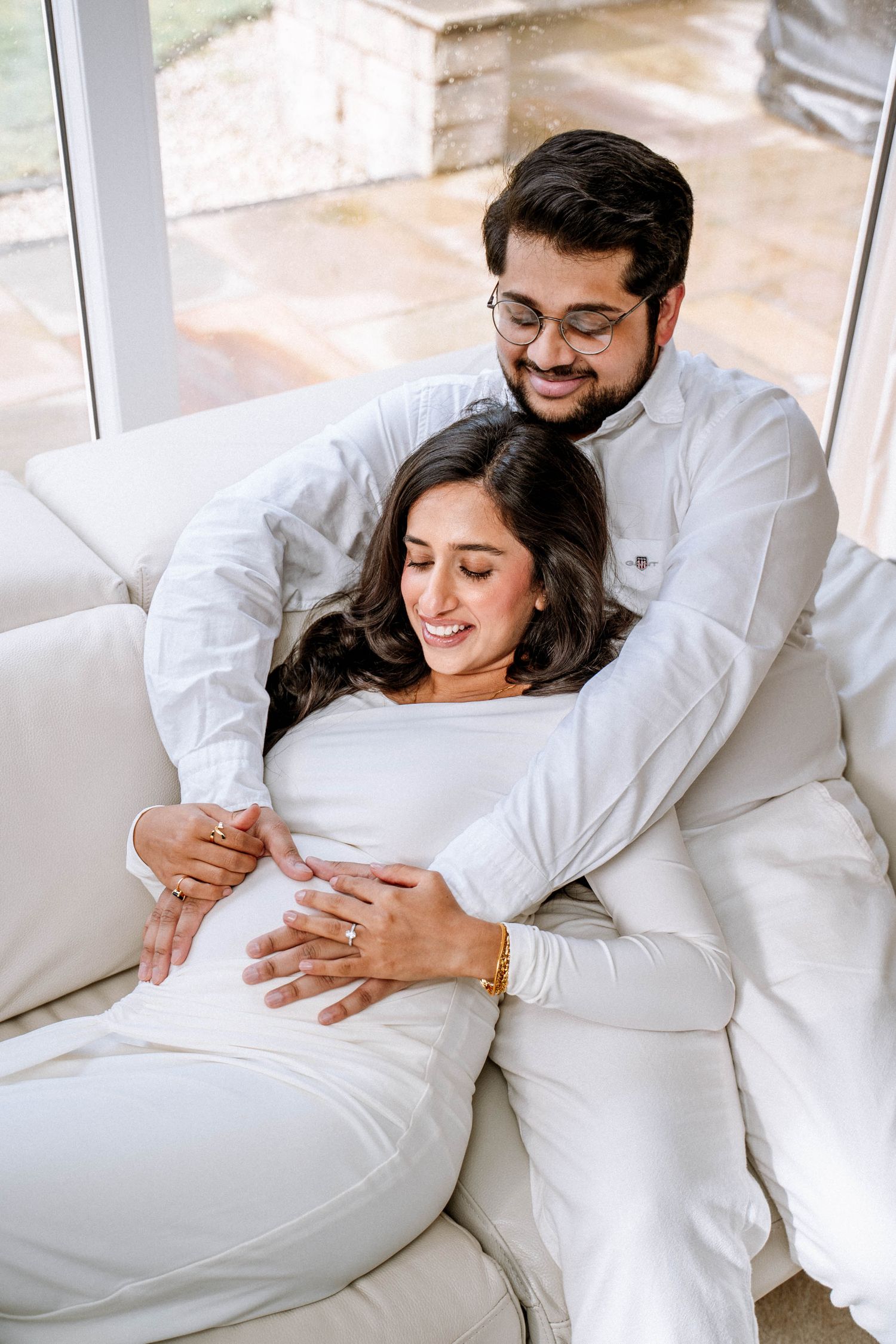 South asian couple looking at baby bump smiling during maternity photography